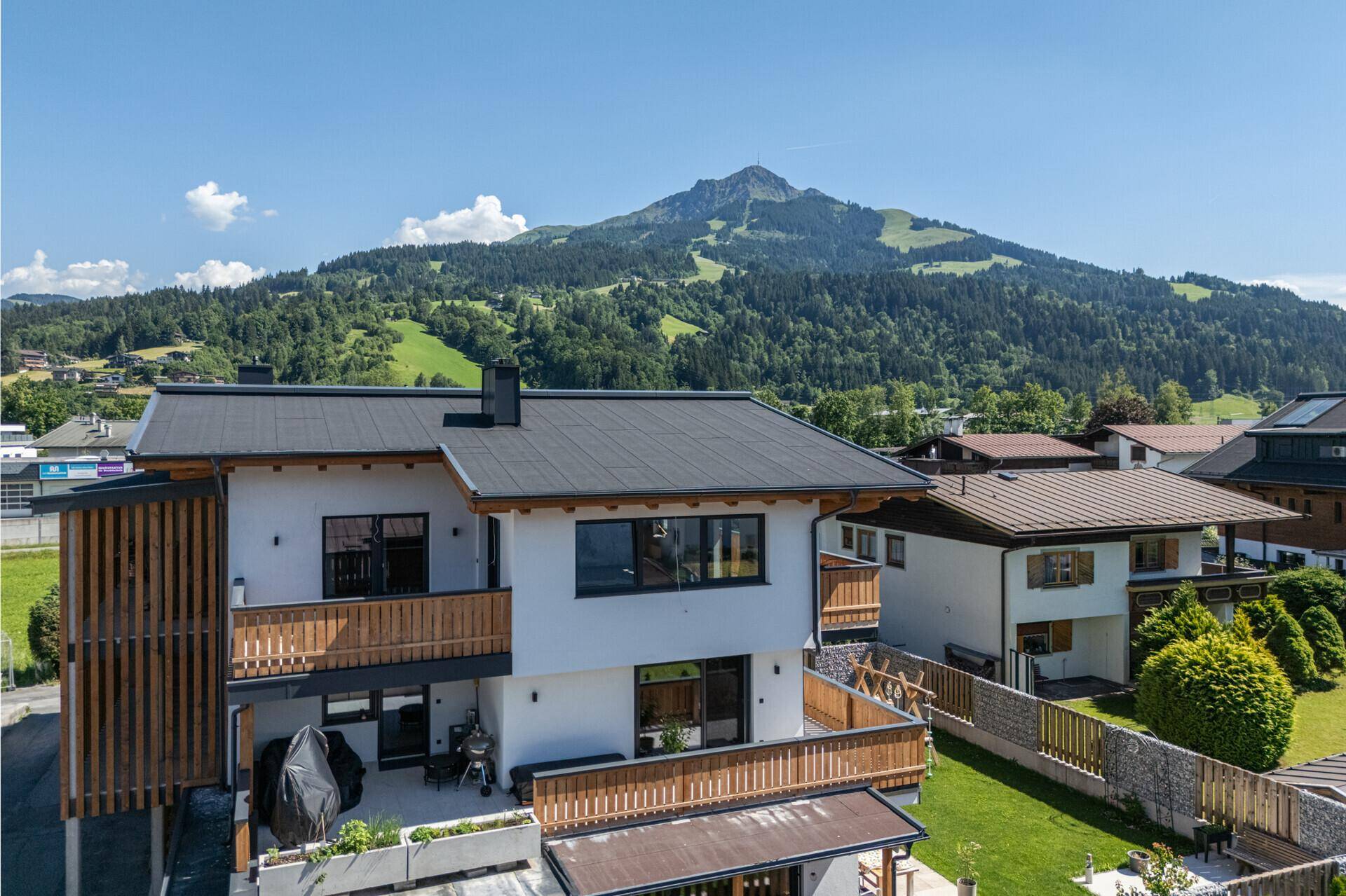 Moderne Wohnanlage mit mehreren Balkonen, Garten und Panoramablick auf die umliegende Berglandschaft.