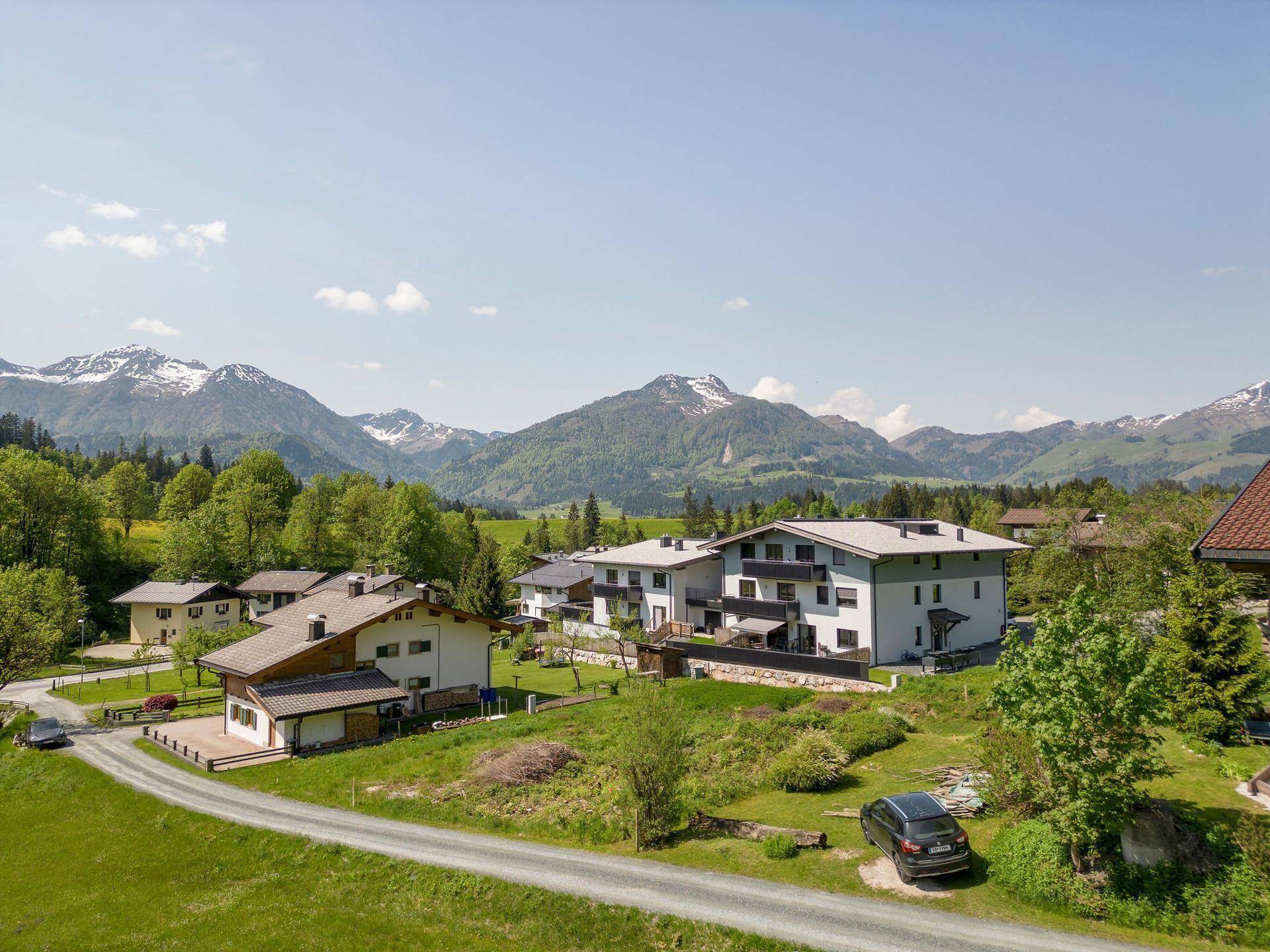 Wohngebäude in einer idyllischen Berglandschaft mit grünen Wiesen und klarem Himmel.
