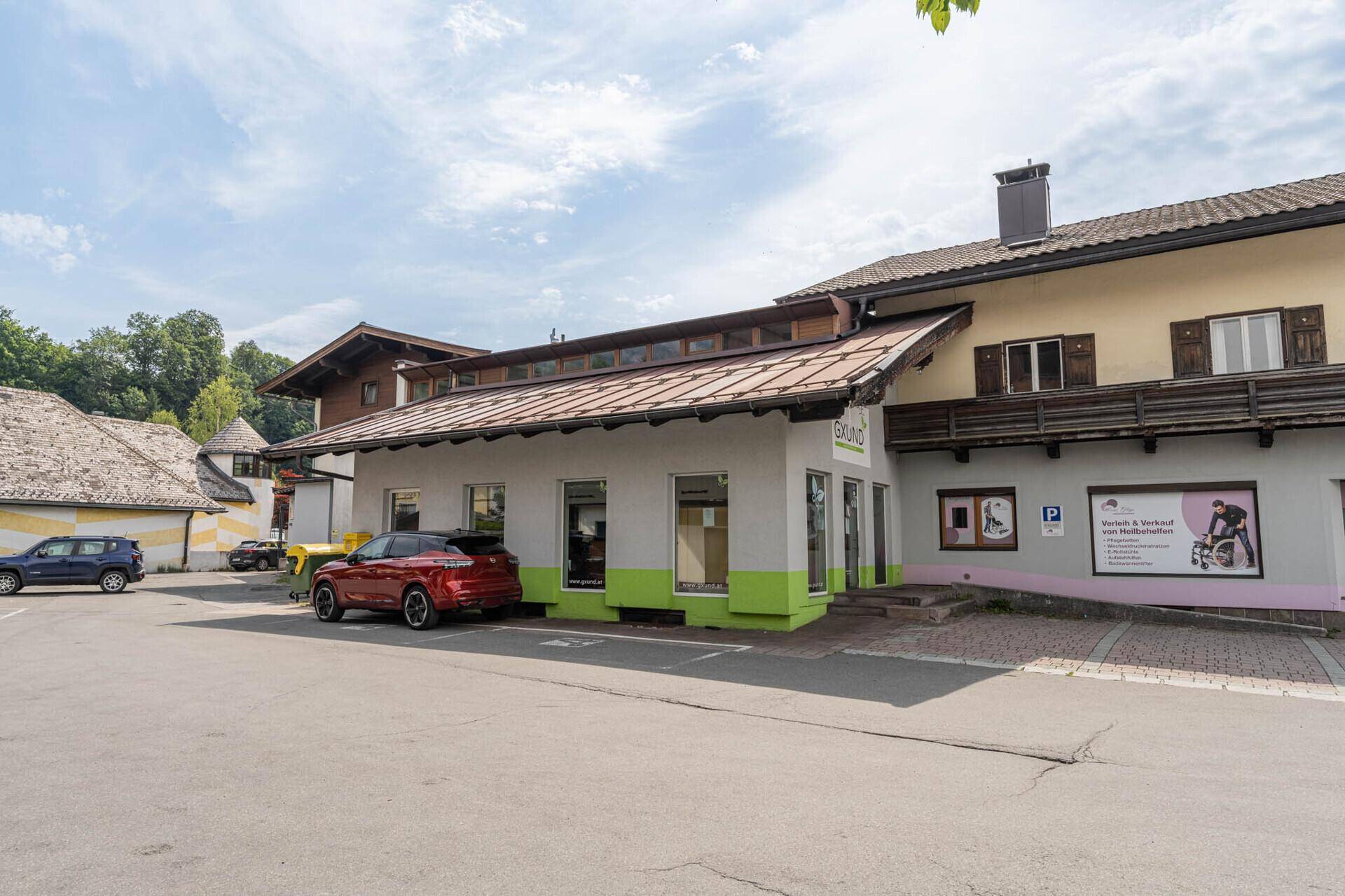 Ansicht des Gebäudes von der Seite mit Parkplätzen und traditioneller Holzverkleidung.