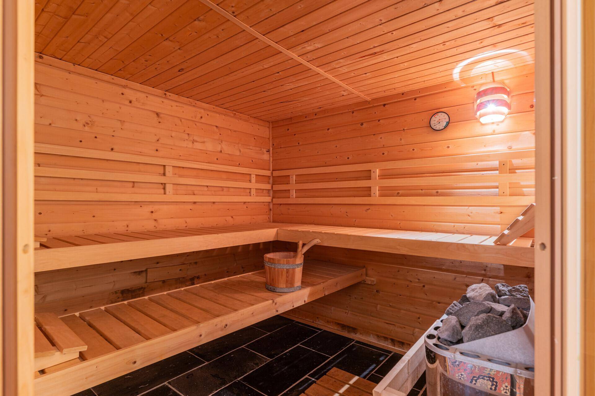 Traditionelle Holzsauna mit mehreren Bänken und einem Saunaofen für Entspannung.