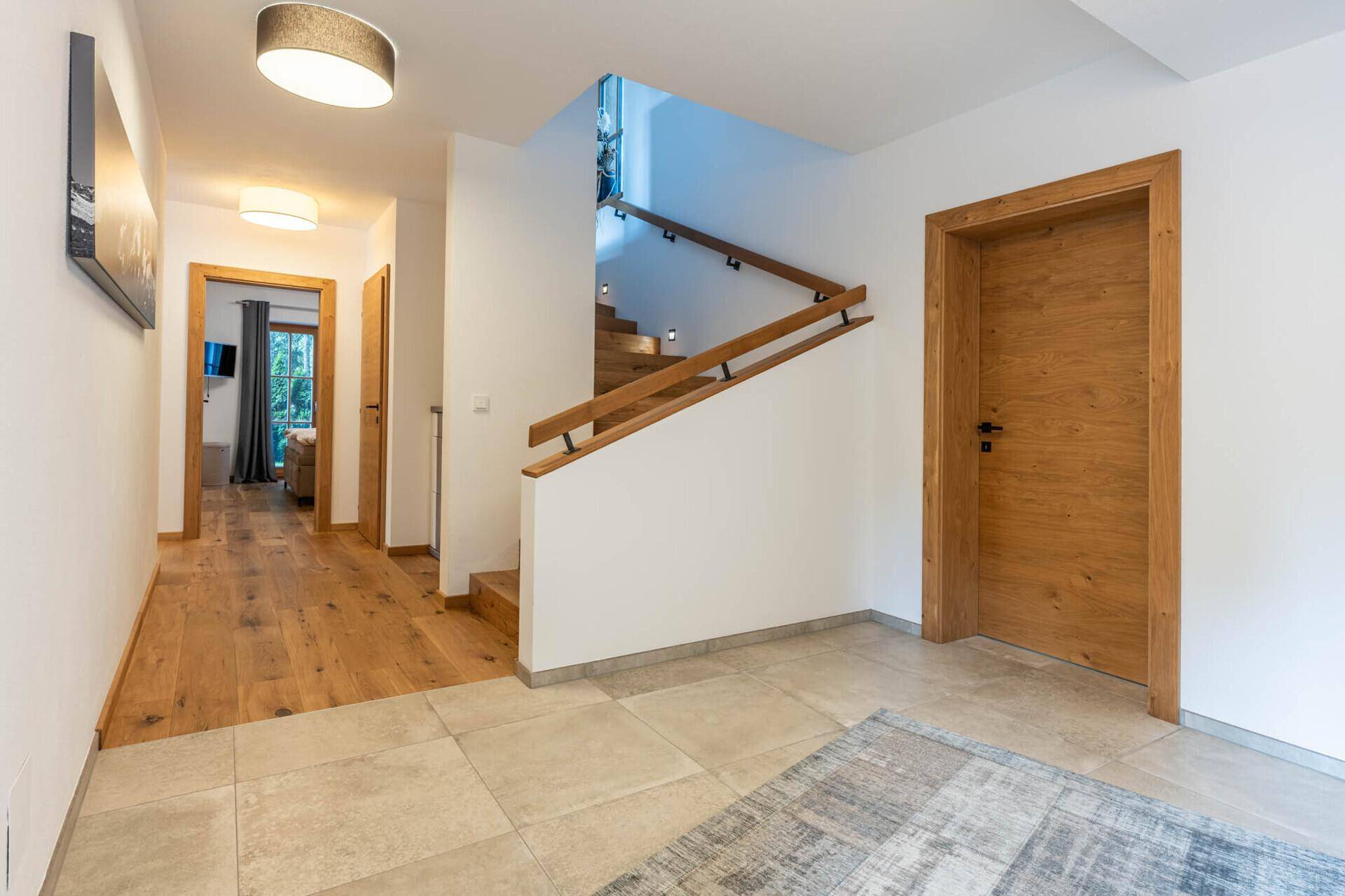 Heller Flur mit Holztreppe, Fliesenboden und Holztüren.