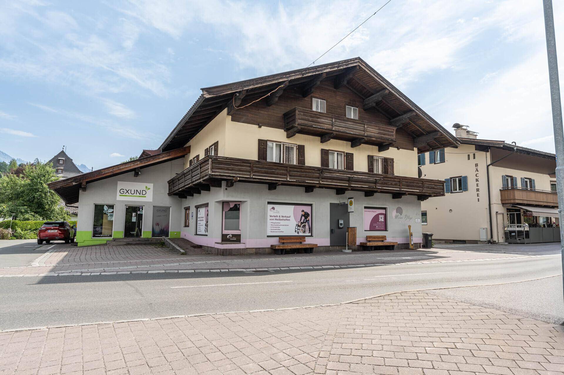 Traditionelles Gebäude mit Holzbalkonen und Geschäften im Erdgeschoss an einer Straße gelegen.