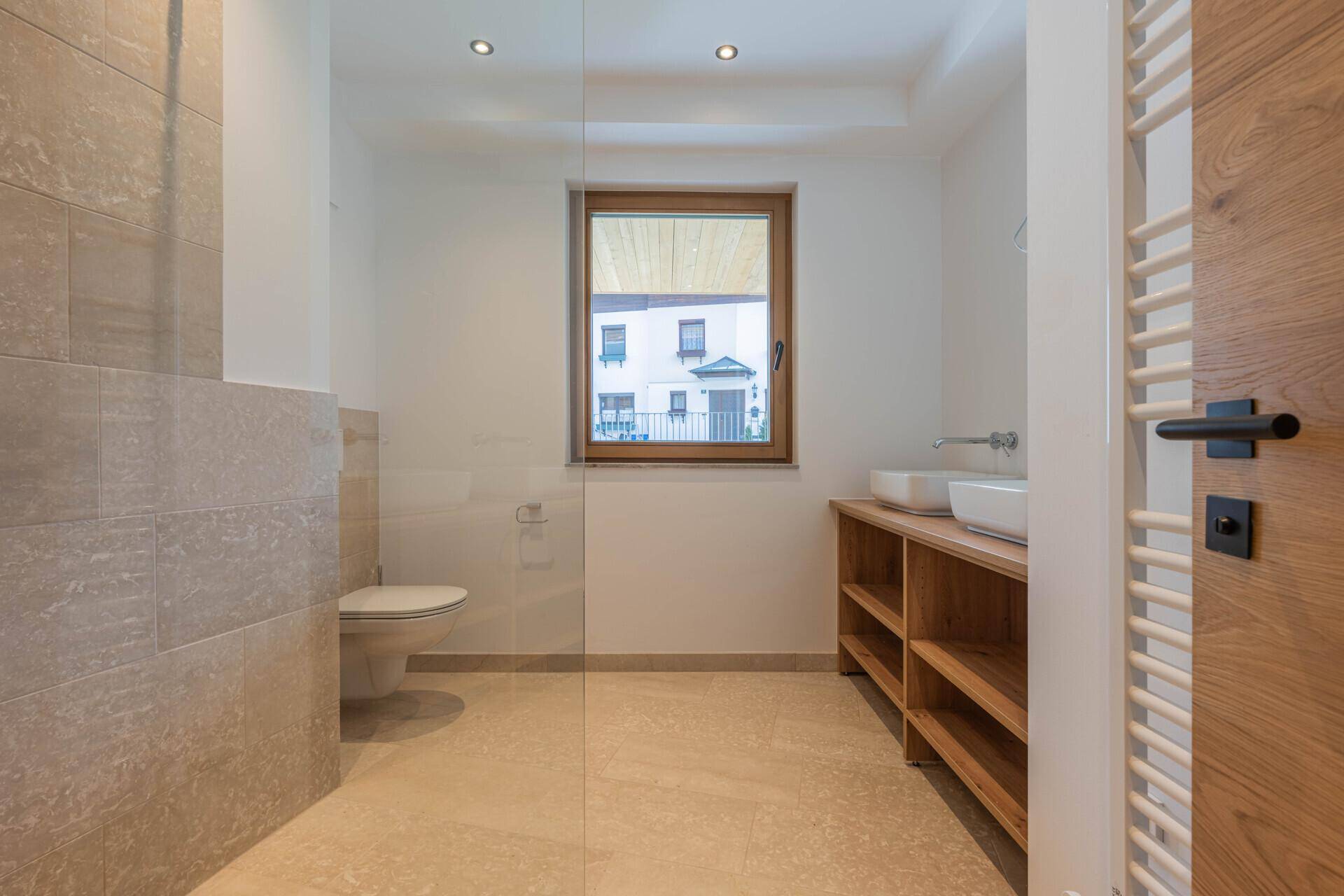 Modernes Badezimmer mit zwei Waschbecken, Dusche und Fenster für Tageslicht.