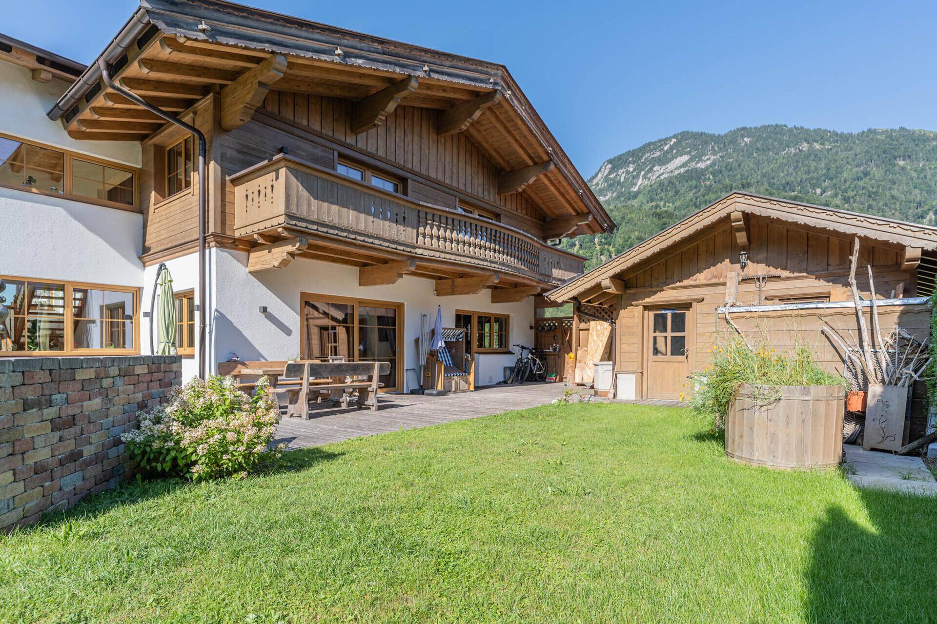 Charmante Hausfassade mit Holzelementen, Balkon und einer einladenden Terrasse.