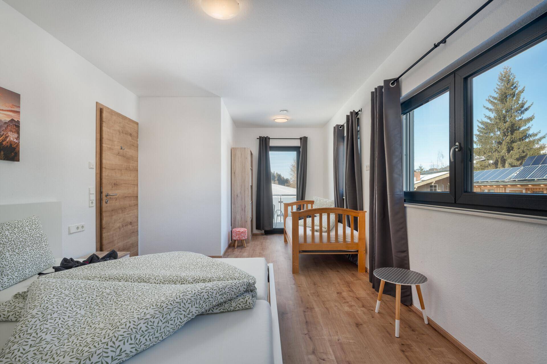 Helles Schlafzimmer mit Holzboden, zwei Einzelbetten und großem Fenster mit Ausblick.