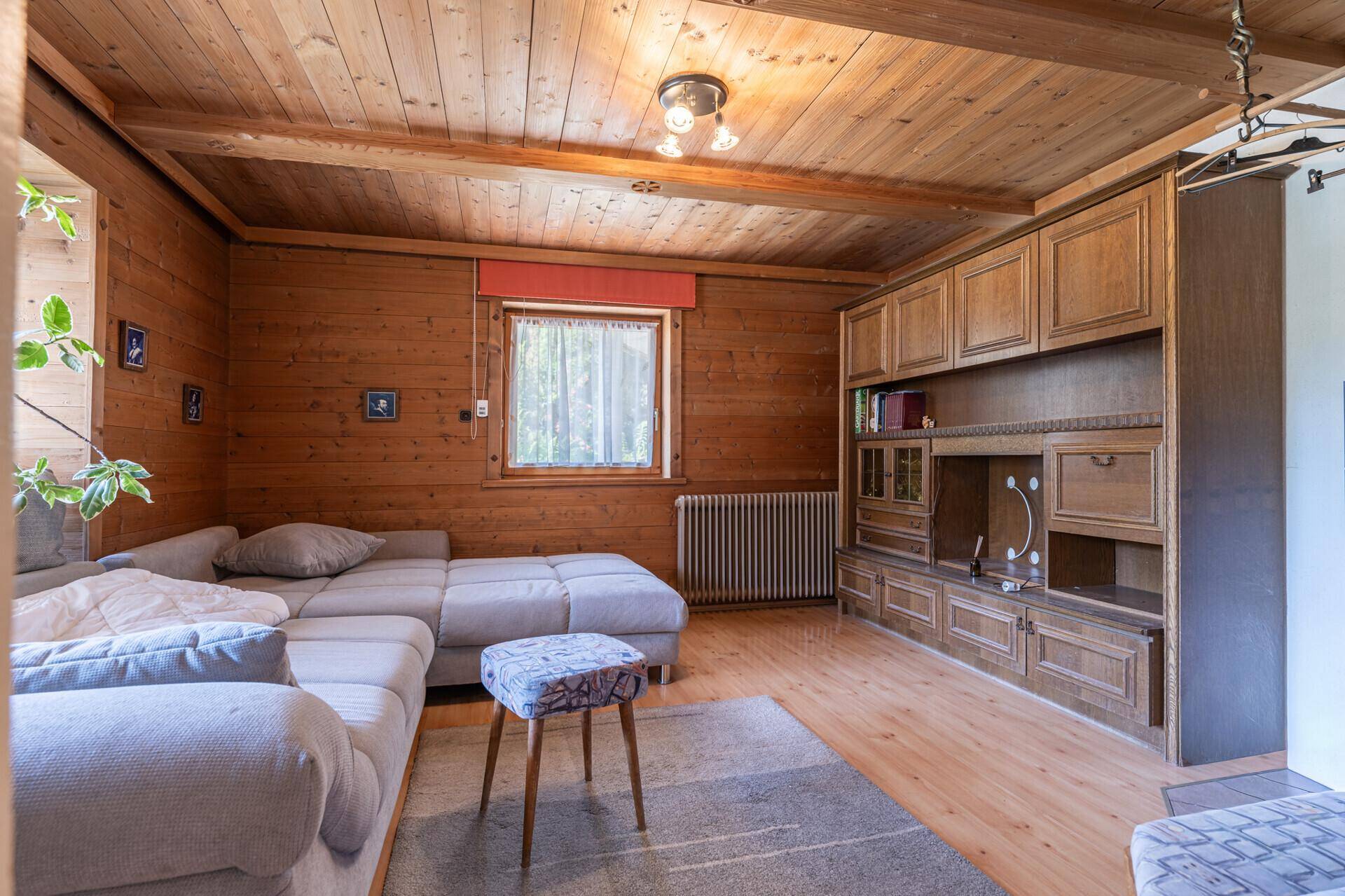 Rustikales Wohnzimmer mit Holztäfelung, Holzbalkendecke und integrierten Holzschränken.