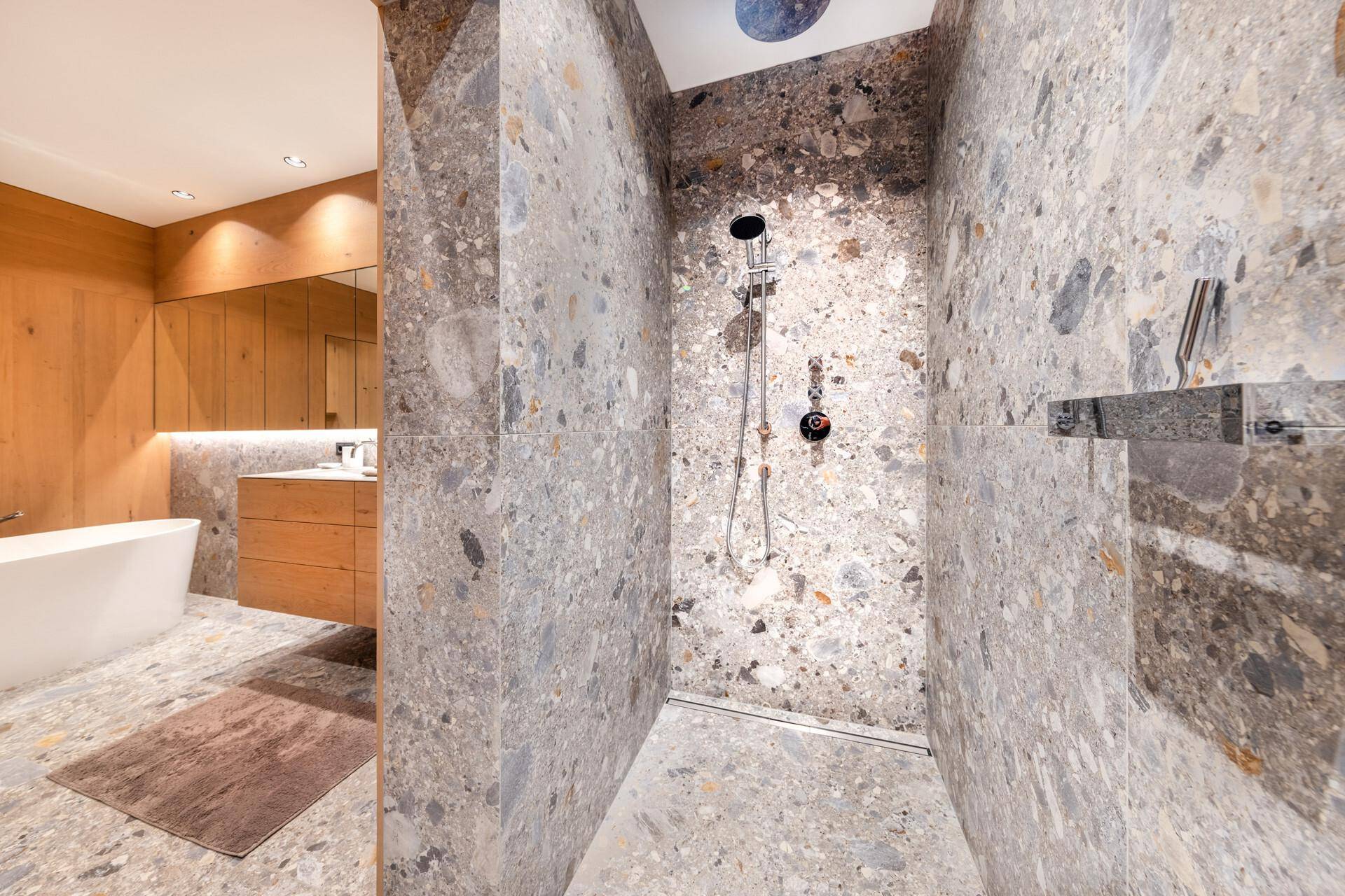 Moderne begehbare Dusche mit Regenduschkopf und eleganten Steinfliesen im luxuriösen Badezimmer.