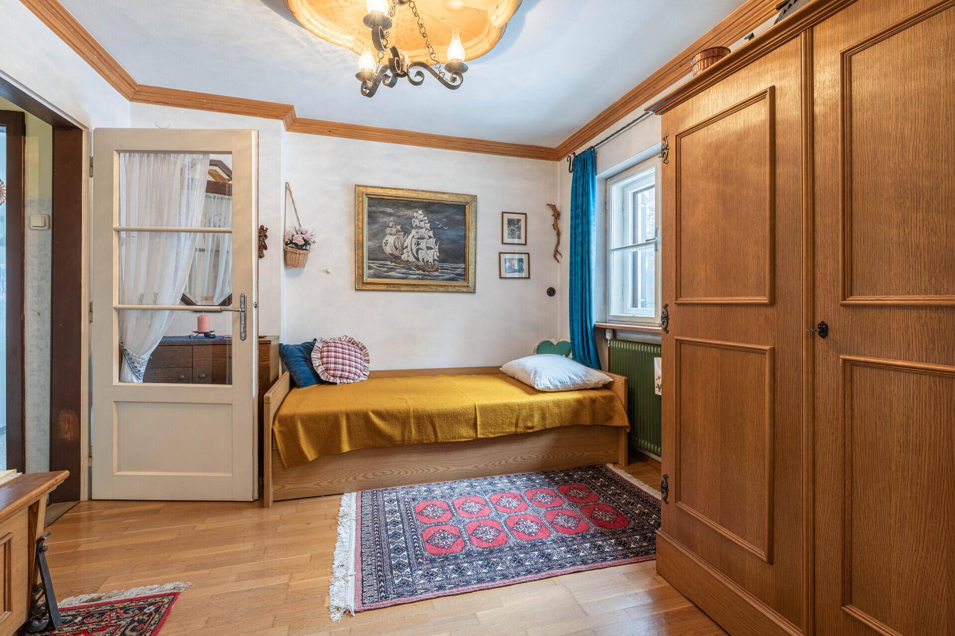 Kleines Schlafzimmer mit Einzelbett, Holzschrank und traditioneller Dekoration, ideal als Gästezimmer.