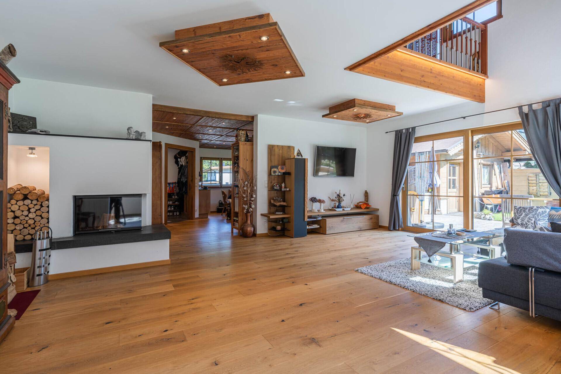 Geräumiges Wohnzimmer mit modernem Kamin, Holzboden und Zugang zur Terrasse.