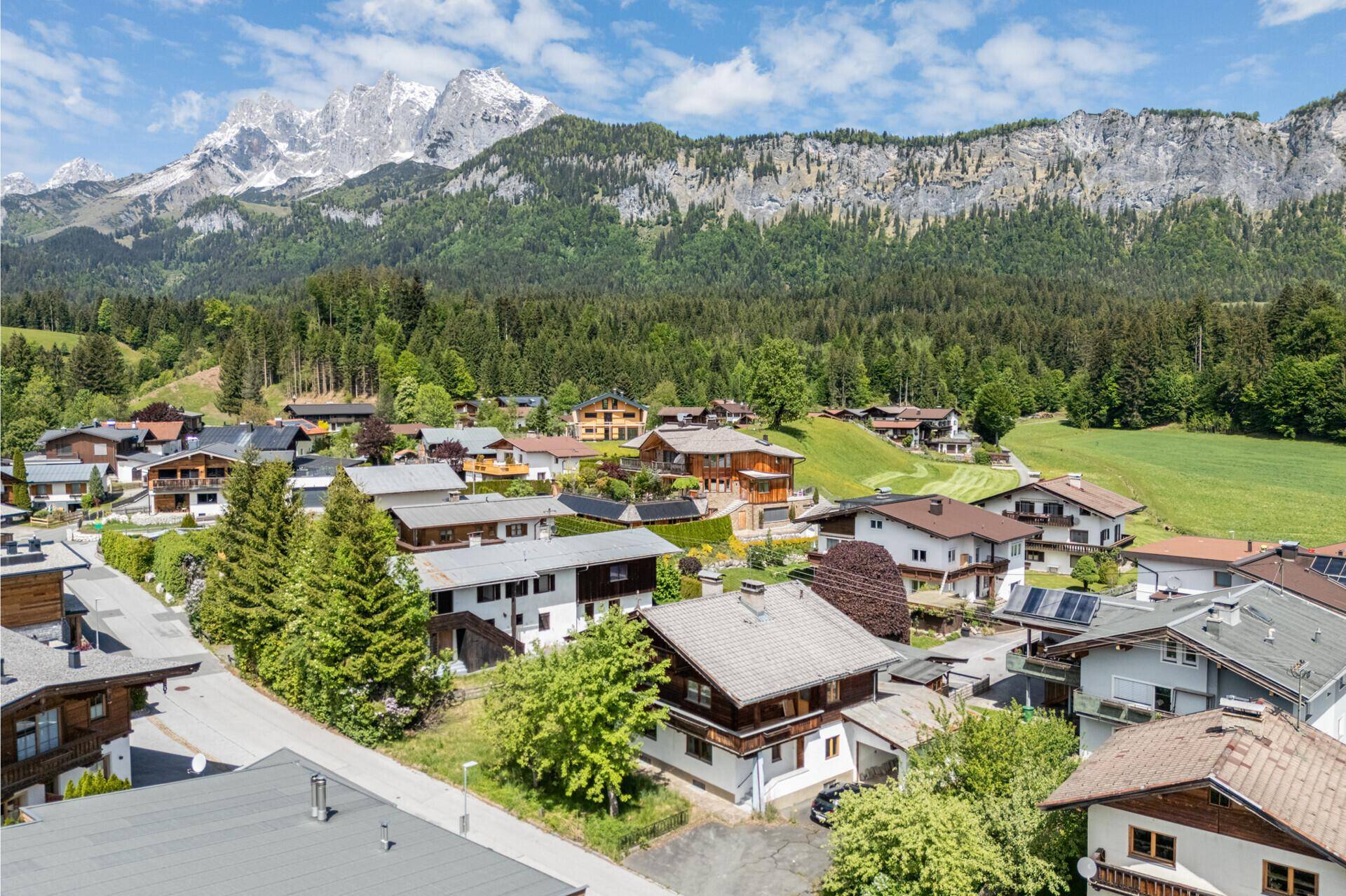 Panoramablick auf ein Bergdorf mit traditionellen Häusern und umliegender Naturlandschaft.