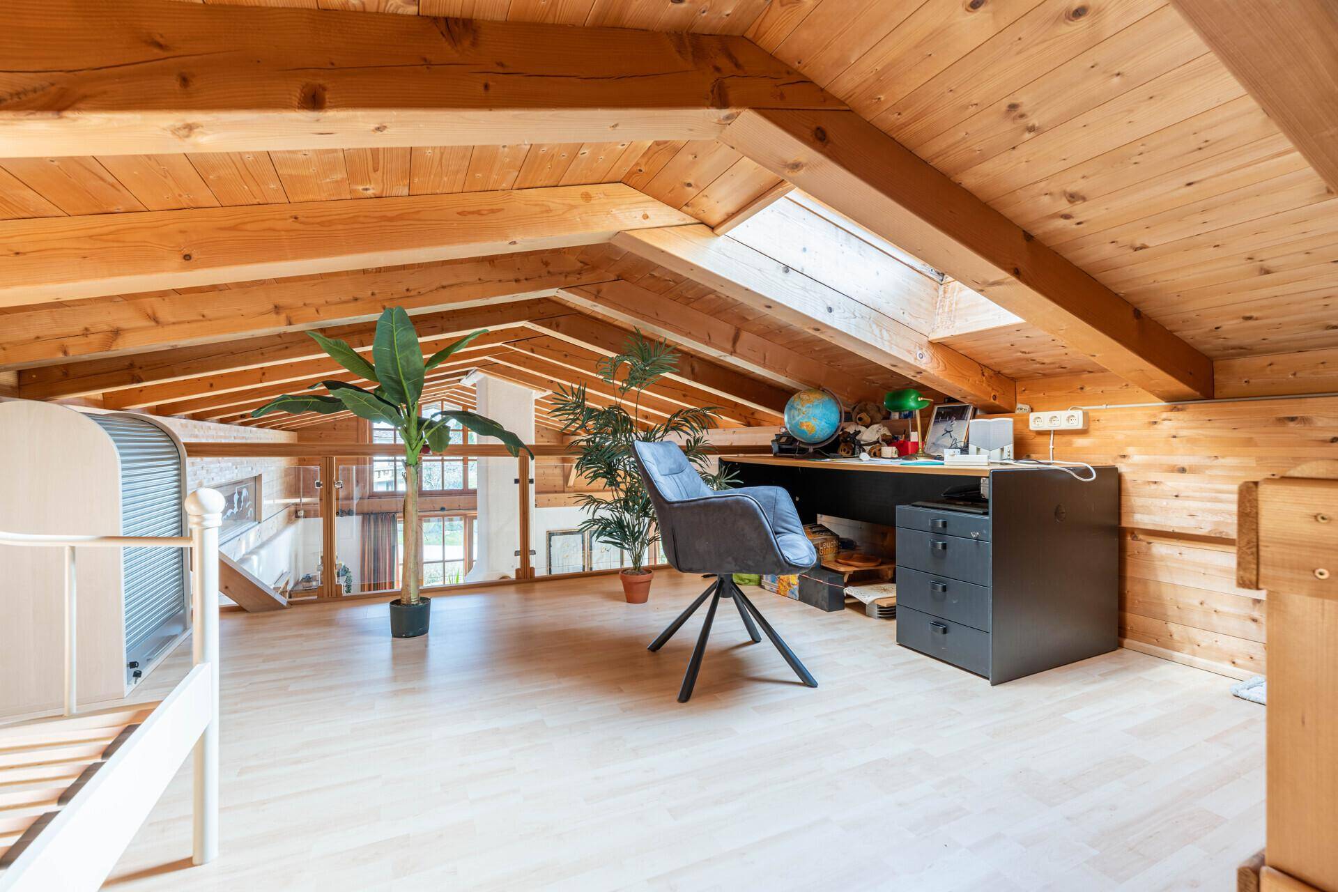 Heller Arbeitsbereich im Dachgeschoss mit Holzbalken, Dachfenster und Blick nach unten.