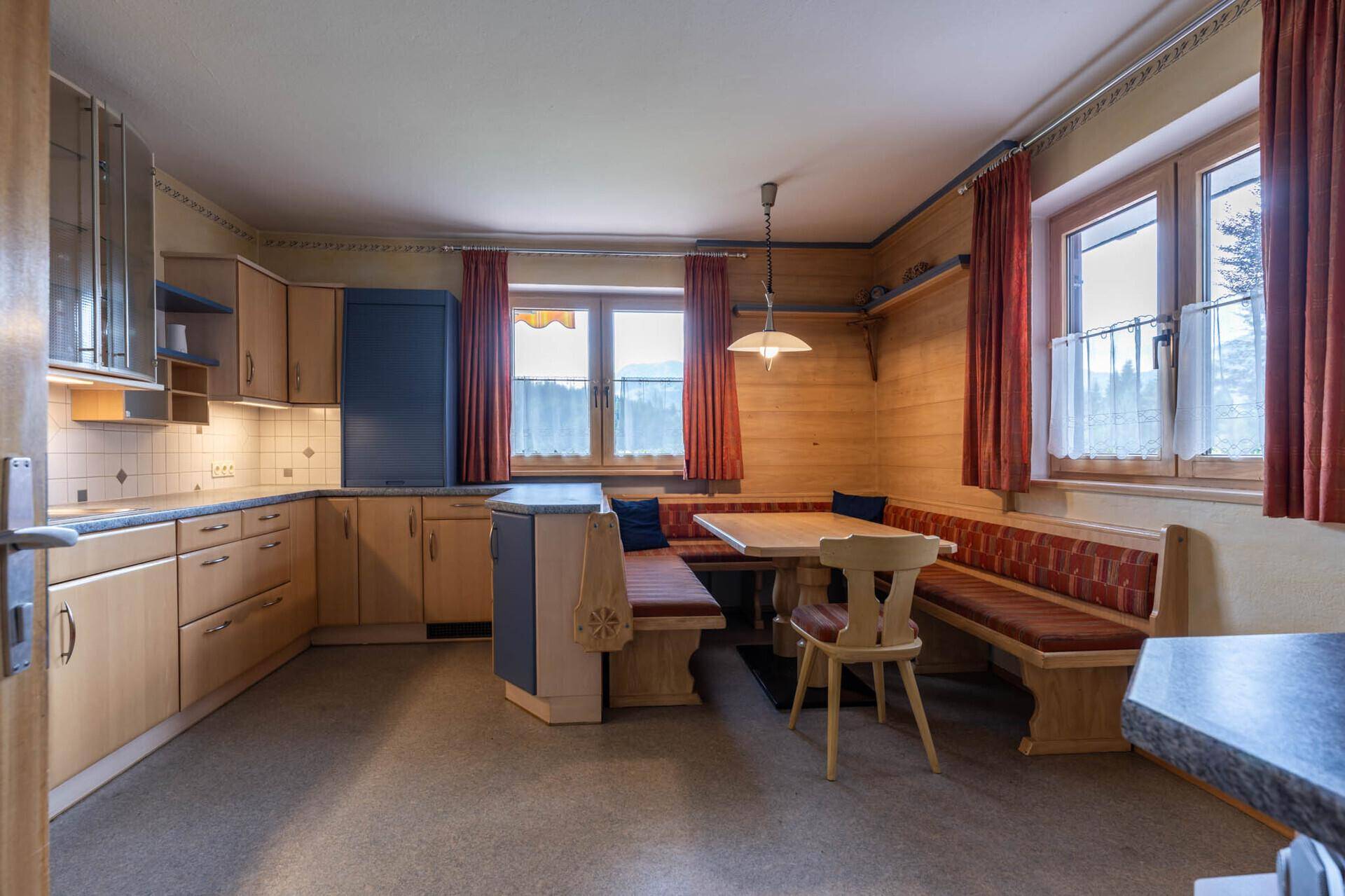 Gemütliche Wohnküche im Landhausstil mit Holztäfelung, Essecke und Blick ins Grüne.