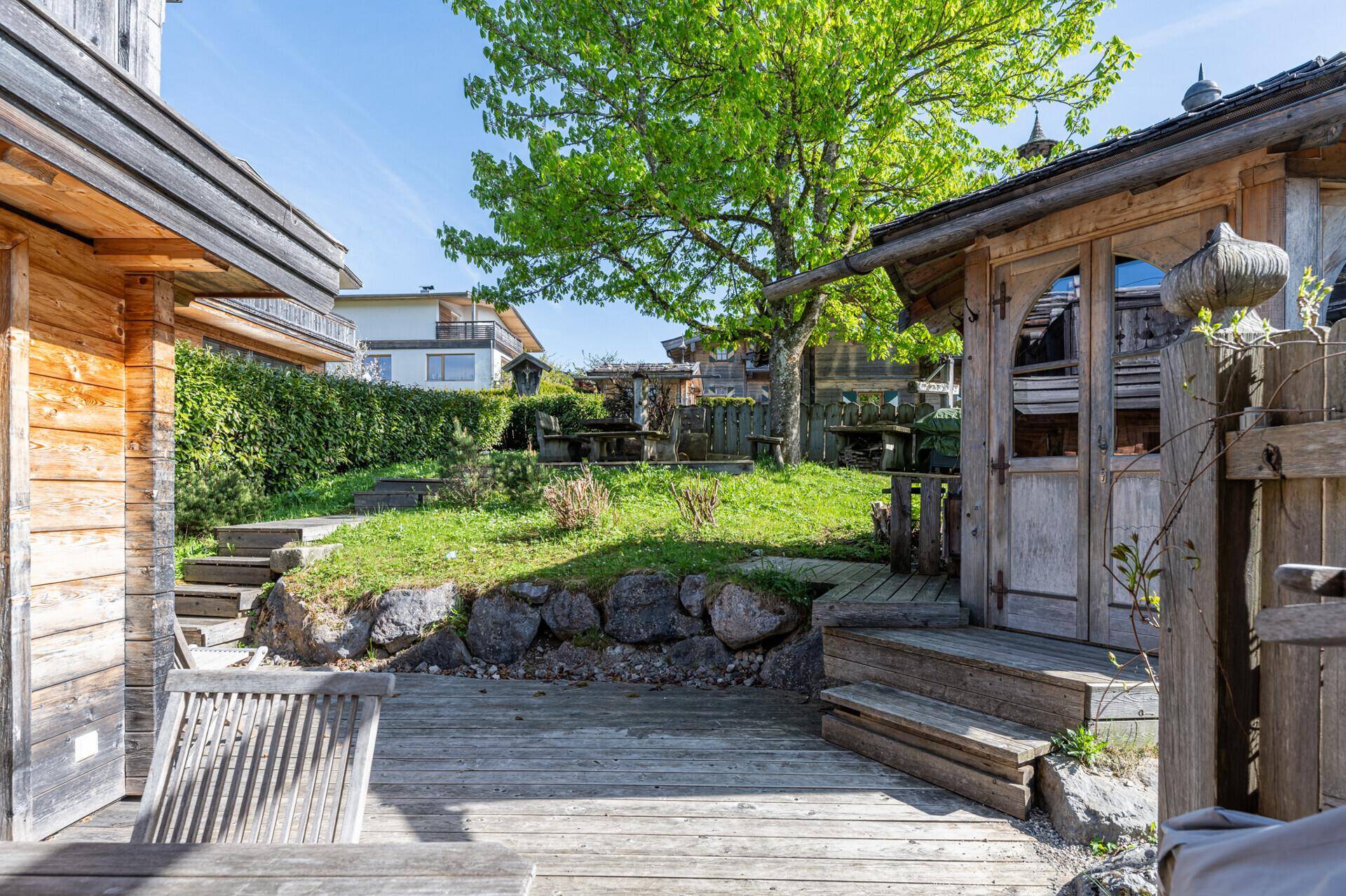 Gepflegter Gartenbereich mit Holzterrasse, Rasenfläche und Blick auf die umliegende Natur.