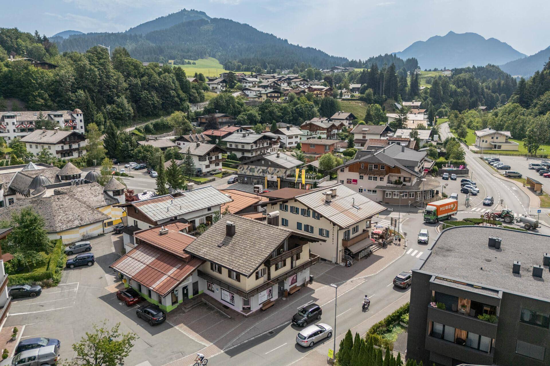 Luftaufnahme eines malerischen Dorfes in den Bergen mit vielen traditionellen Häusern und grüner Umgebung.