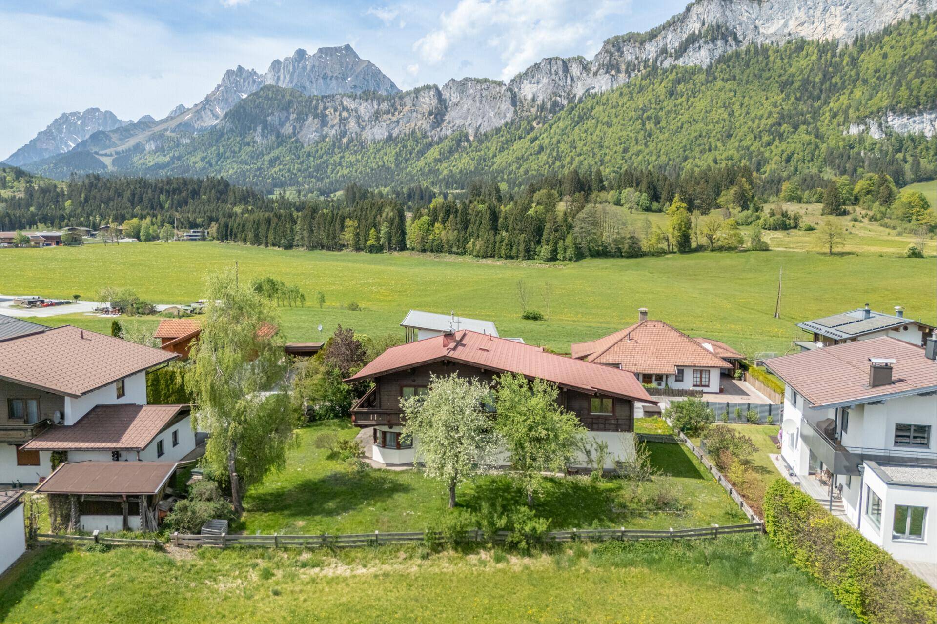 Luftaufnahme eines traditionellen Hauses mit Garten und Bergblick in ländlicher Umgebung.