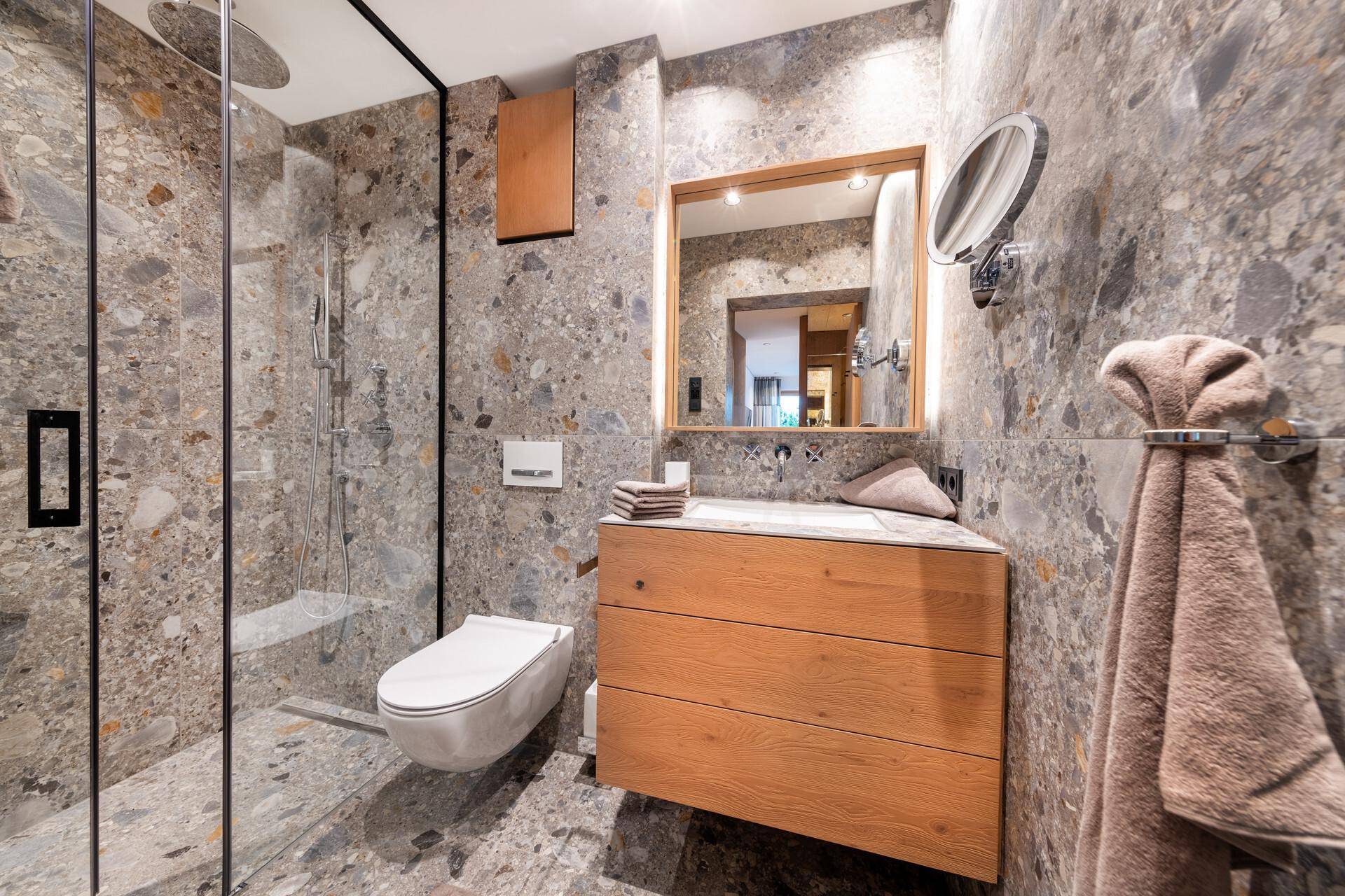 Modernes Badezimmer mit begehbarer Dusche, Steinfliesen und schwebendem Waschtisch.