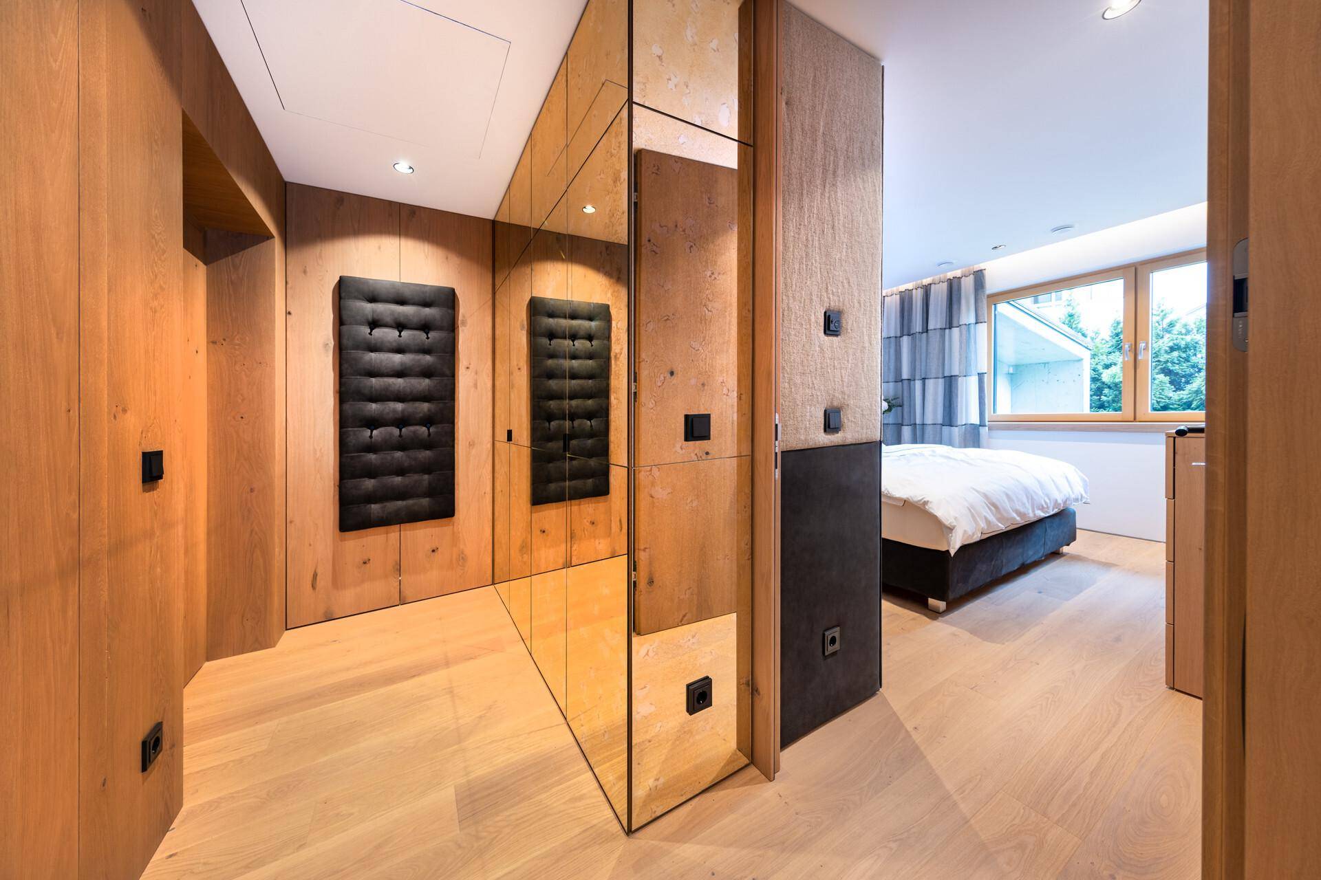Heller Flur mit Holzverkleidung und Spiegelfronten, der den Zugang zum Schlafzimmer ermöglicht.