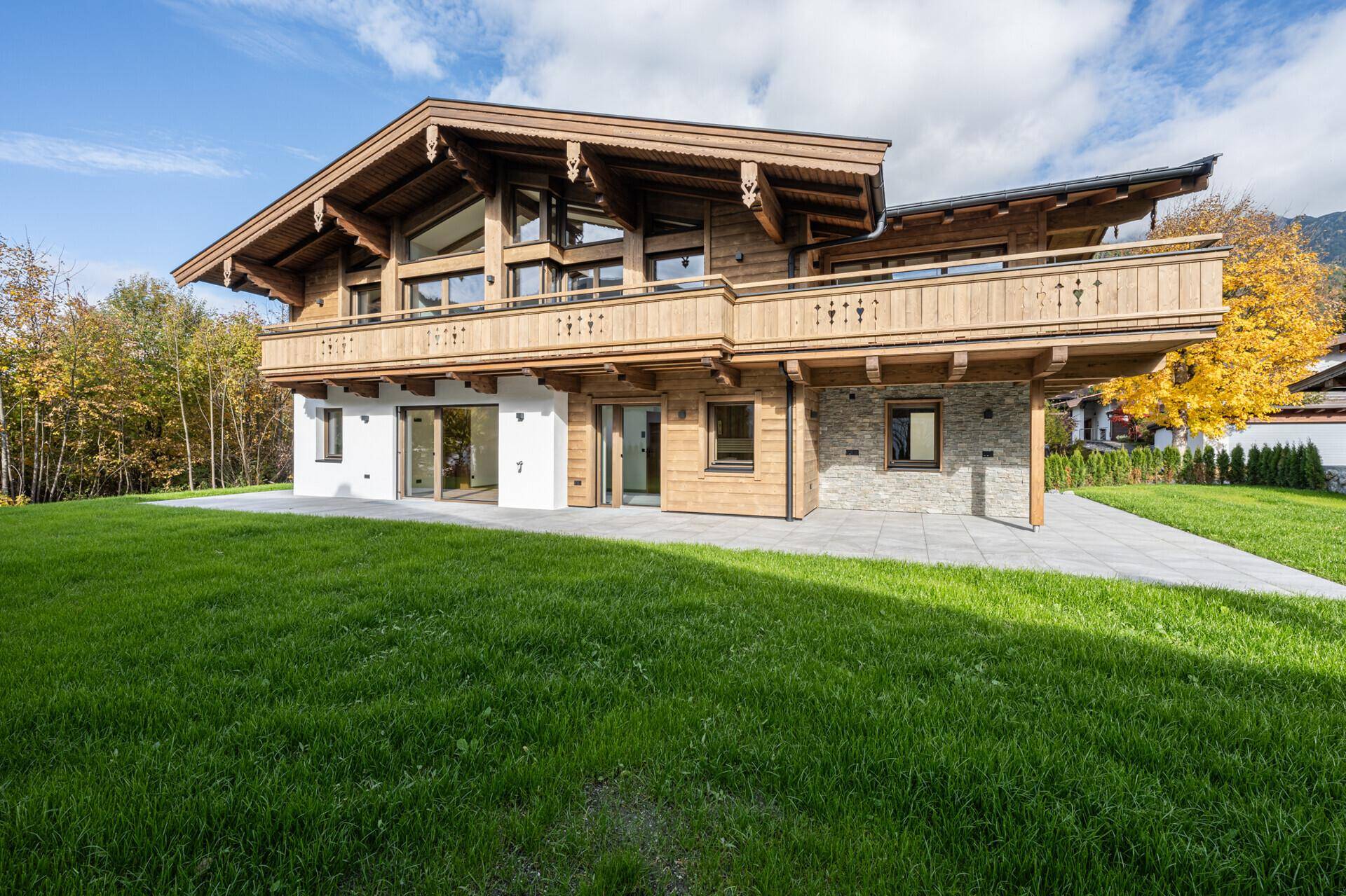 Frontansicht des modernen Chalets mit gepflegtem Garten und Bergblick.