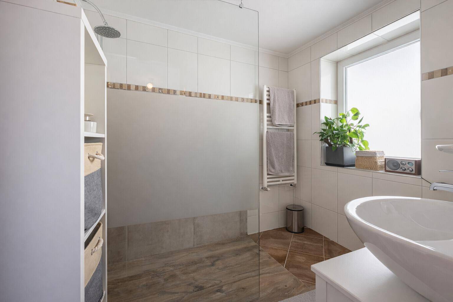 Modernes Badezimmer mit ebenerdiger Dusche, großem Fenster und stilvollen Fliesen.