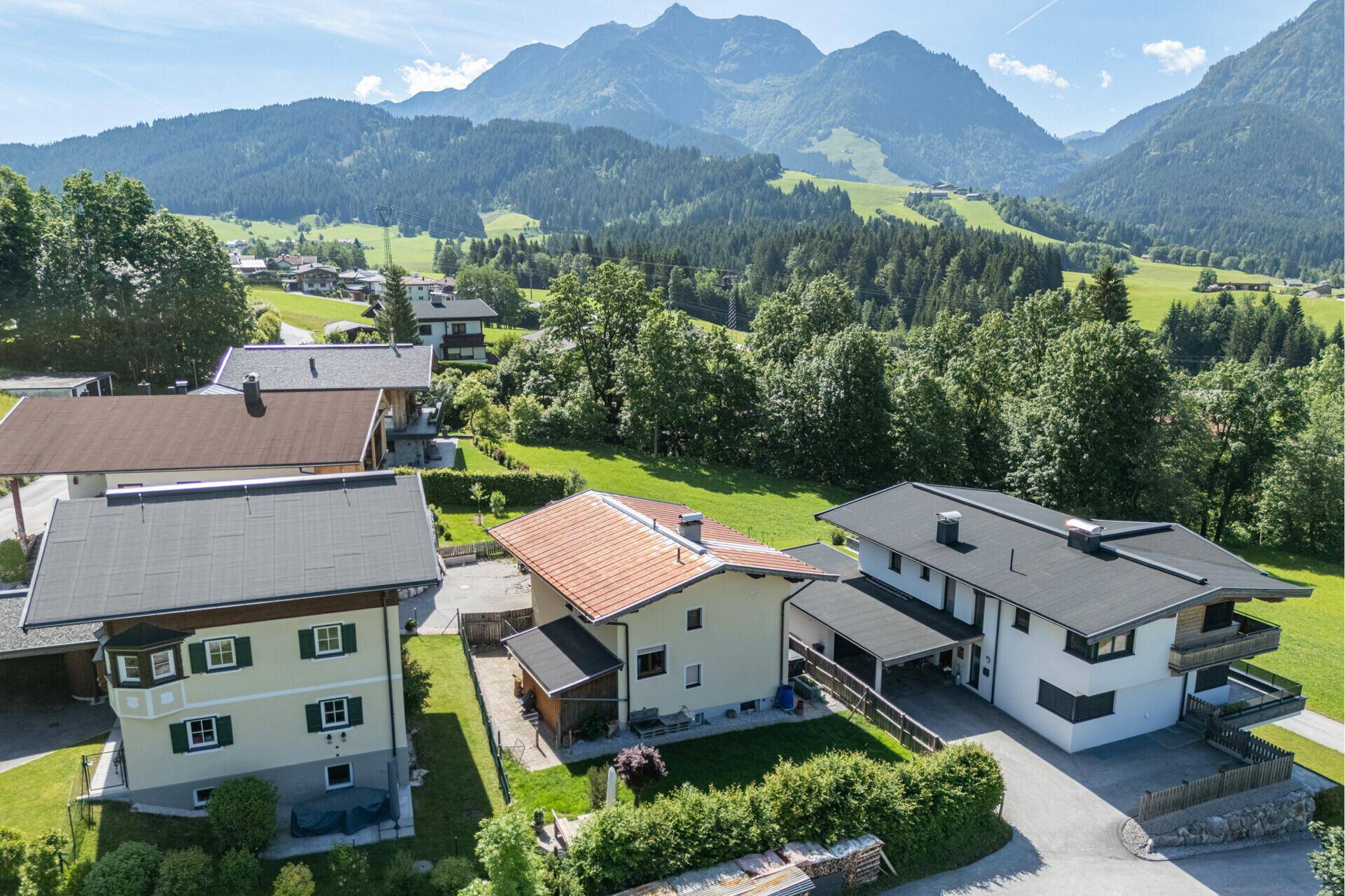 Panoramablick aus der Vogelperspektive auf Wohnhäuser eingebettet in eine grüne Berglandschaft.