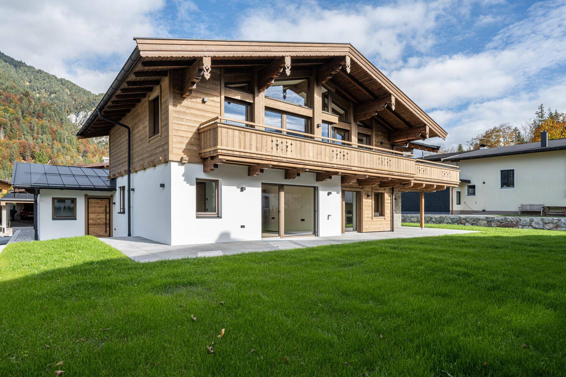 Neubau-Chalet mit großzügiger Rasenfläche und alpiner Architektur.