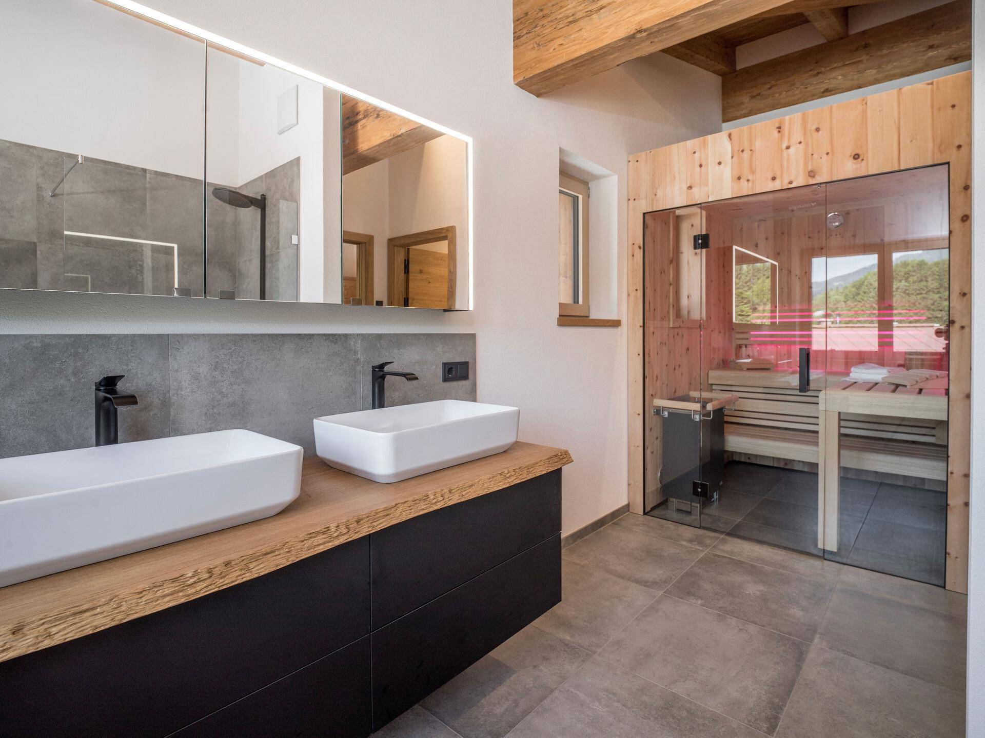 Modernes Badezimmer mit Doppelwaschbecken, Spiegelschrank und integrierter Sauna.