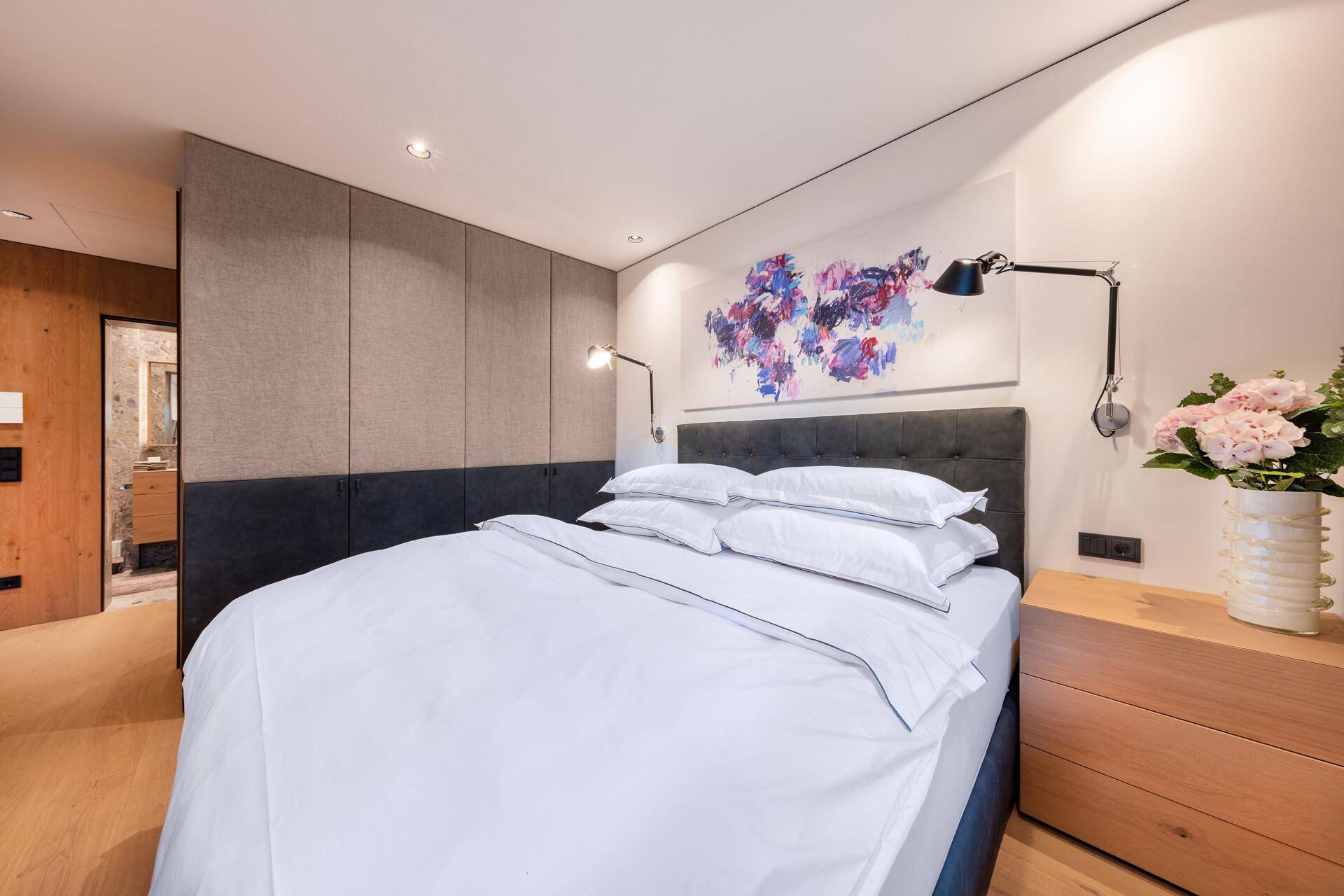 Gemütliches Schlafzimmer mit Doppelbett, Holzboden und moderner Wandgestaltung.