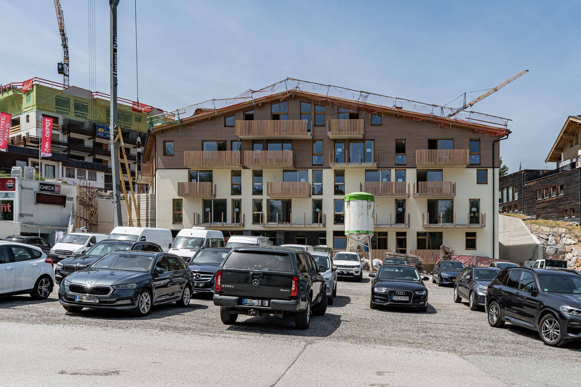 Neubau eines Gebäudes mit Holzelementen und Balkonen, umgeben von einer Baustelle.