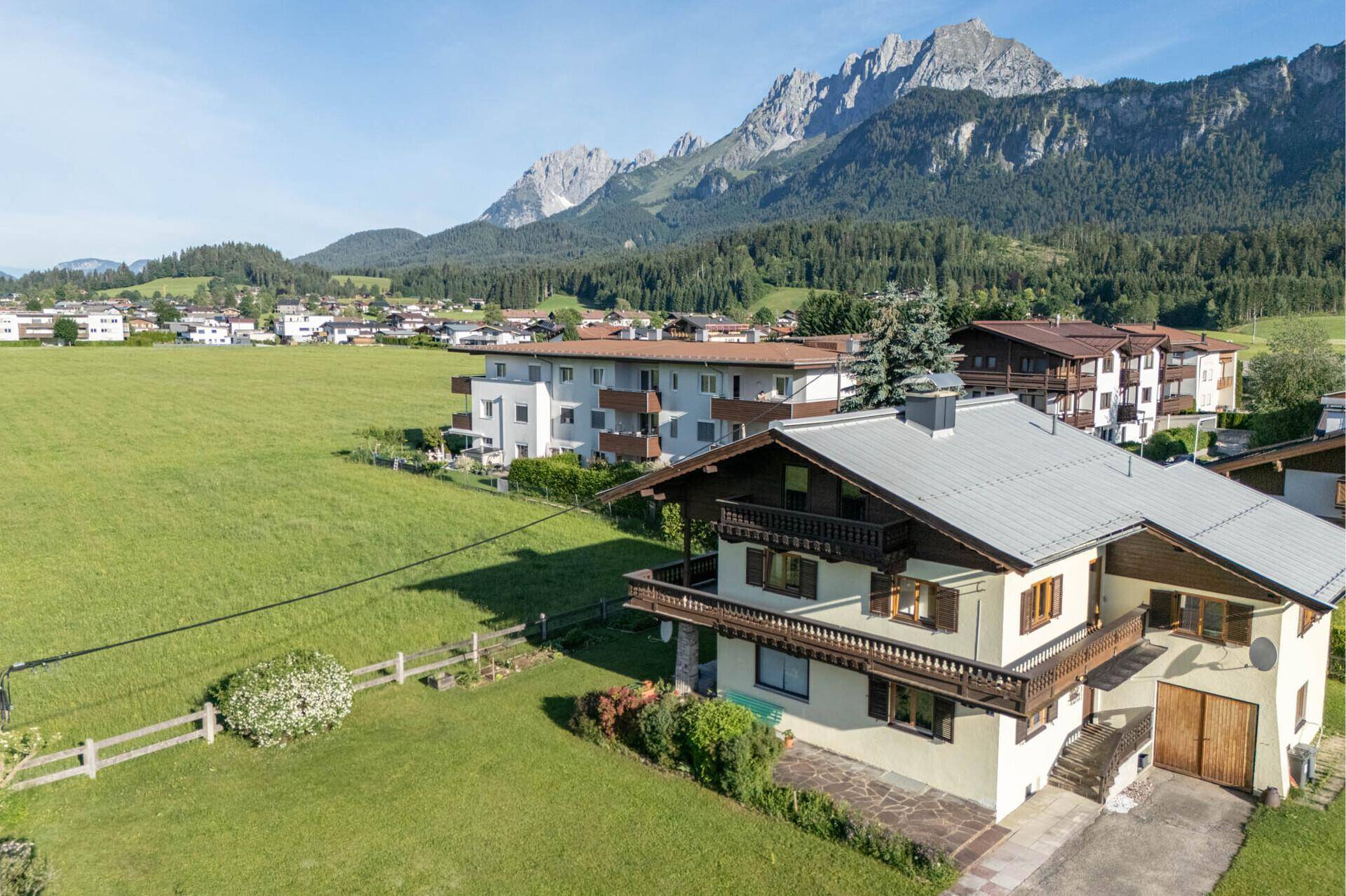 Panoramablick auf ein charmantes Haus mit traditioneller Architektur, umgeben von grünen Wiesen und Bergen.