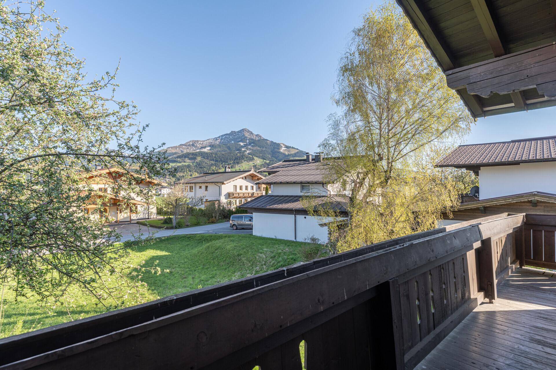 Balkon mit Holzboden und Blick auf die umliegende Berglandschaft und Nachbarschaft.