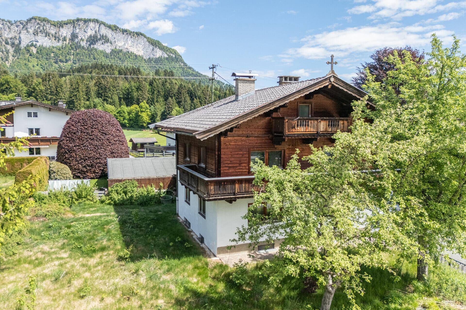 Charmantes Holzhaus im alpinen Stil mit Balkonen und Blick auf die umliegende Bergwelt.