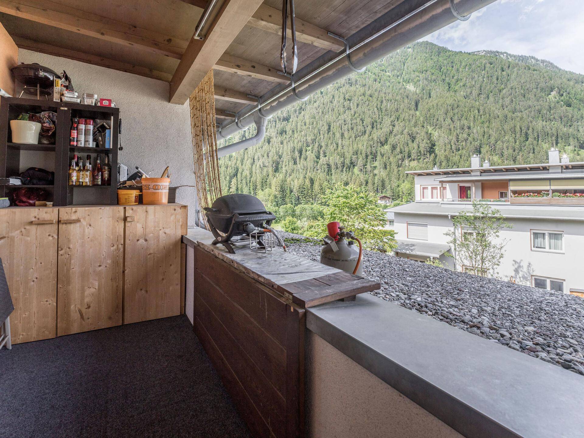 Balkon mit Grillbereich und atemberaubendem Blick auf die bewaldeten Berge.