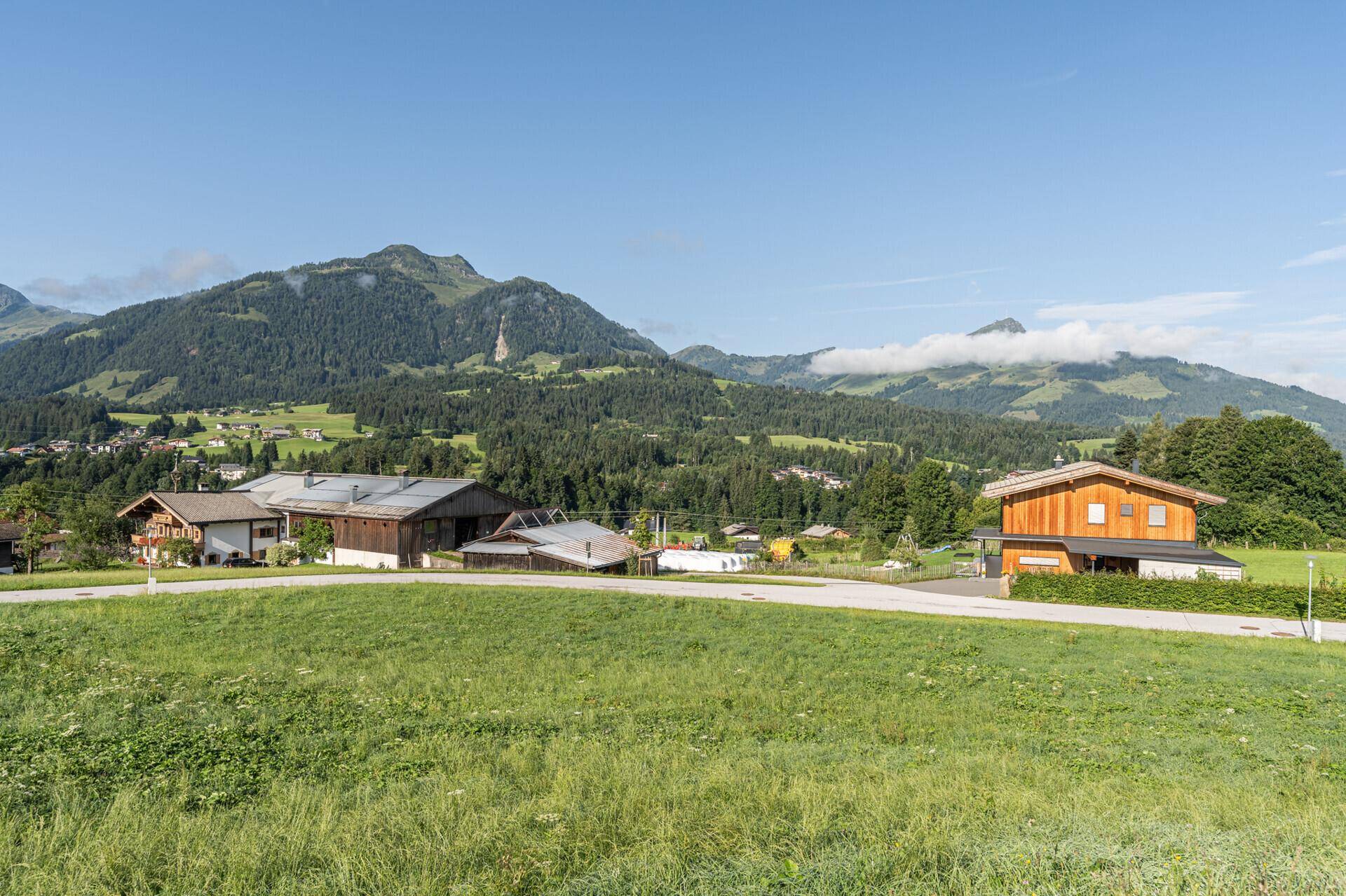Idyllische Landschaft mit mehreren Häusern und weitem Blick auf die bewaldeten Berge und Täler.