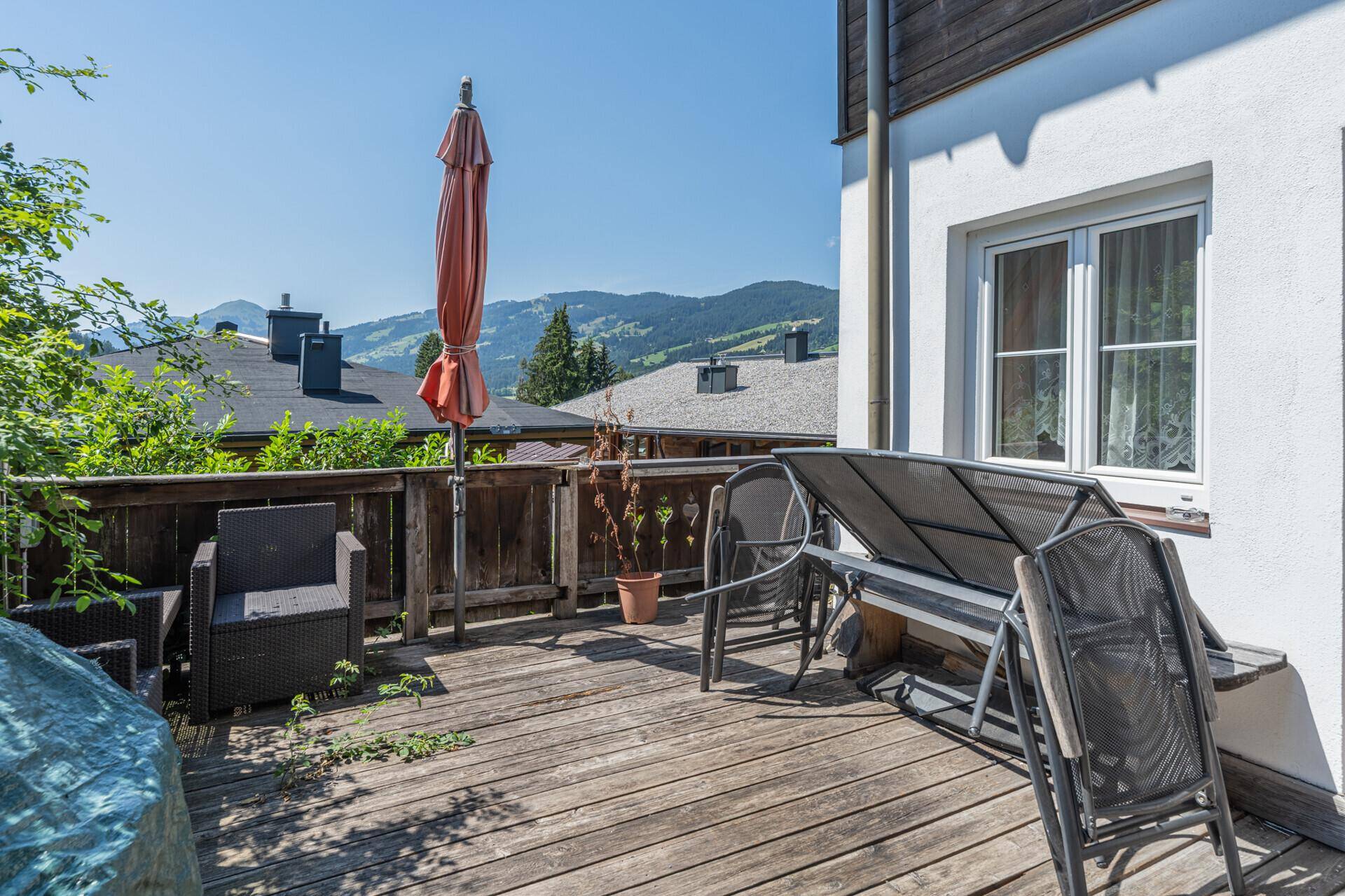 Sonnige Holzterrasse mit Liegestühlen und Blick auf die umliegende Berglandschaft.