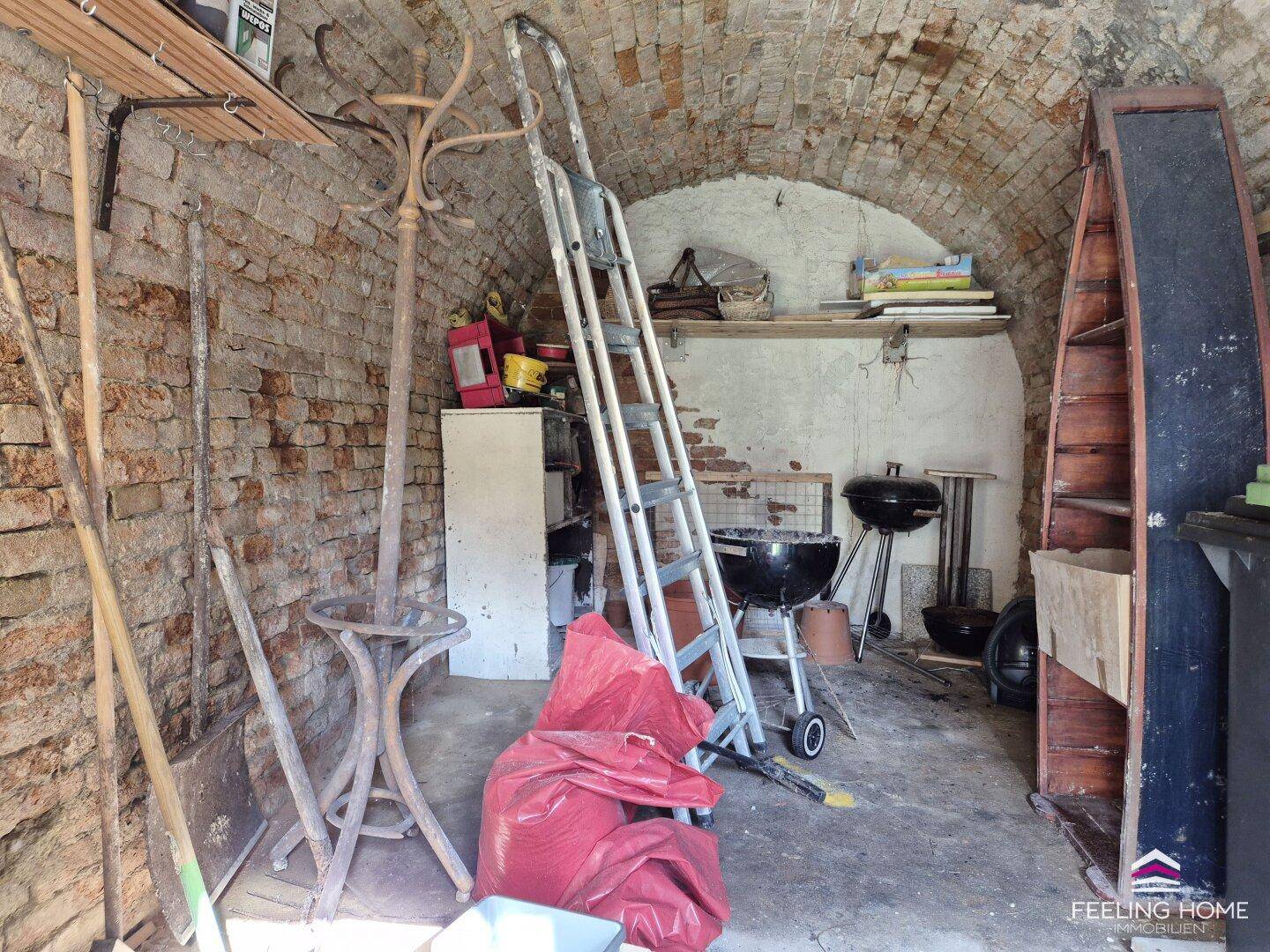 Rustikaler Lagerraum mit freiliegenden Ziegelwänden, Gewölbedecke und verschiedenen Haushaltsutensilien.
