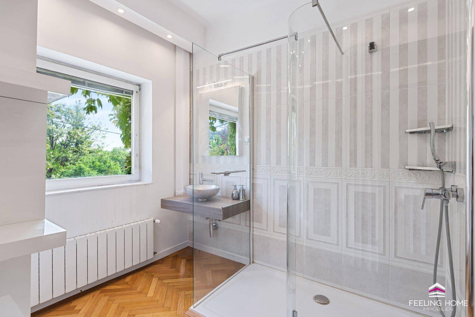 Modernes Badezimmer mit begehbarer Dusche, stilvollem Waschbecken und Fischgrätparkett.