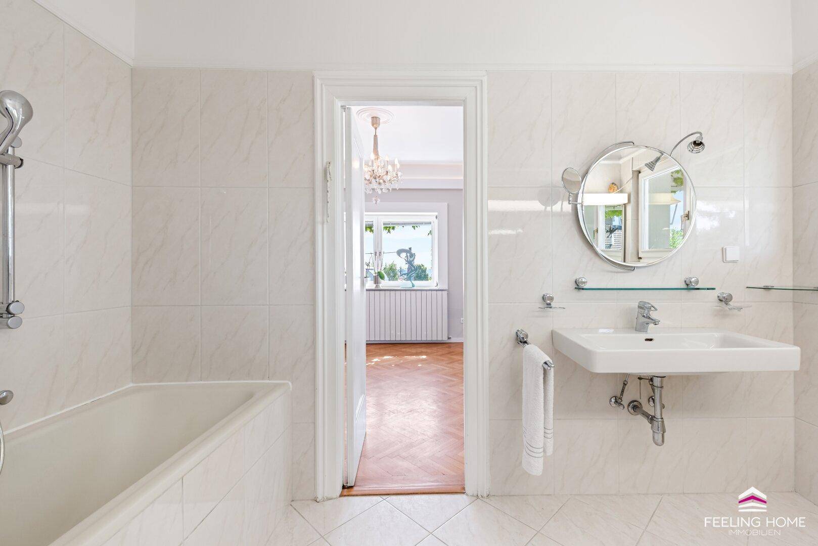 Helles Badezimmer mit Badewanne, Wandfliesen und modernem Waschbecken.
