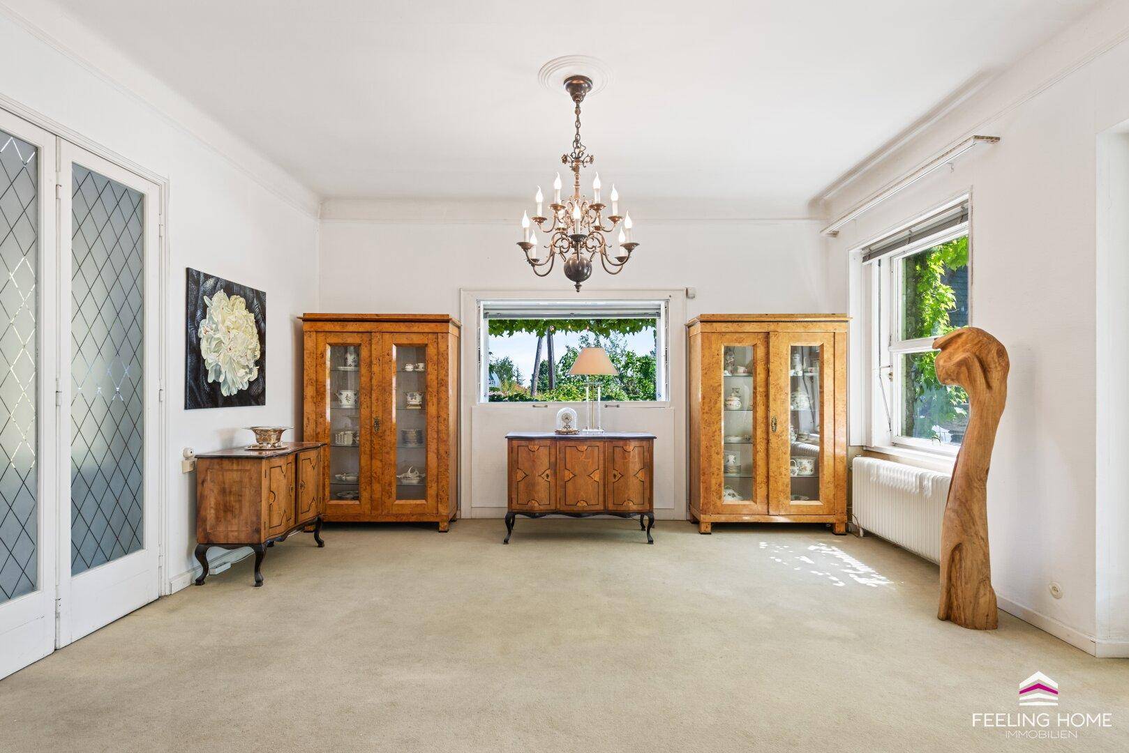 Klassischer Essbereich mit Teppichboden, eleganten Holzschränken und einem Kronleuchter.