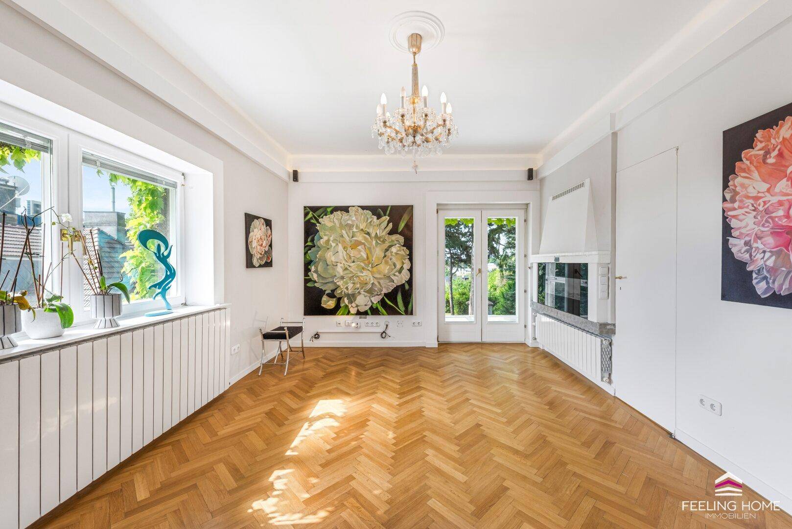Elegantes Wohnzimmer mit Fischgrätparkett, Kamin und Zugang zu einem Balkon.