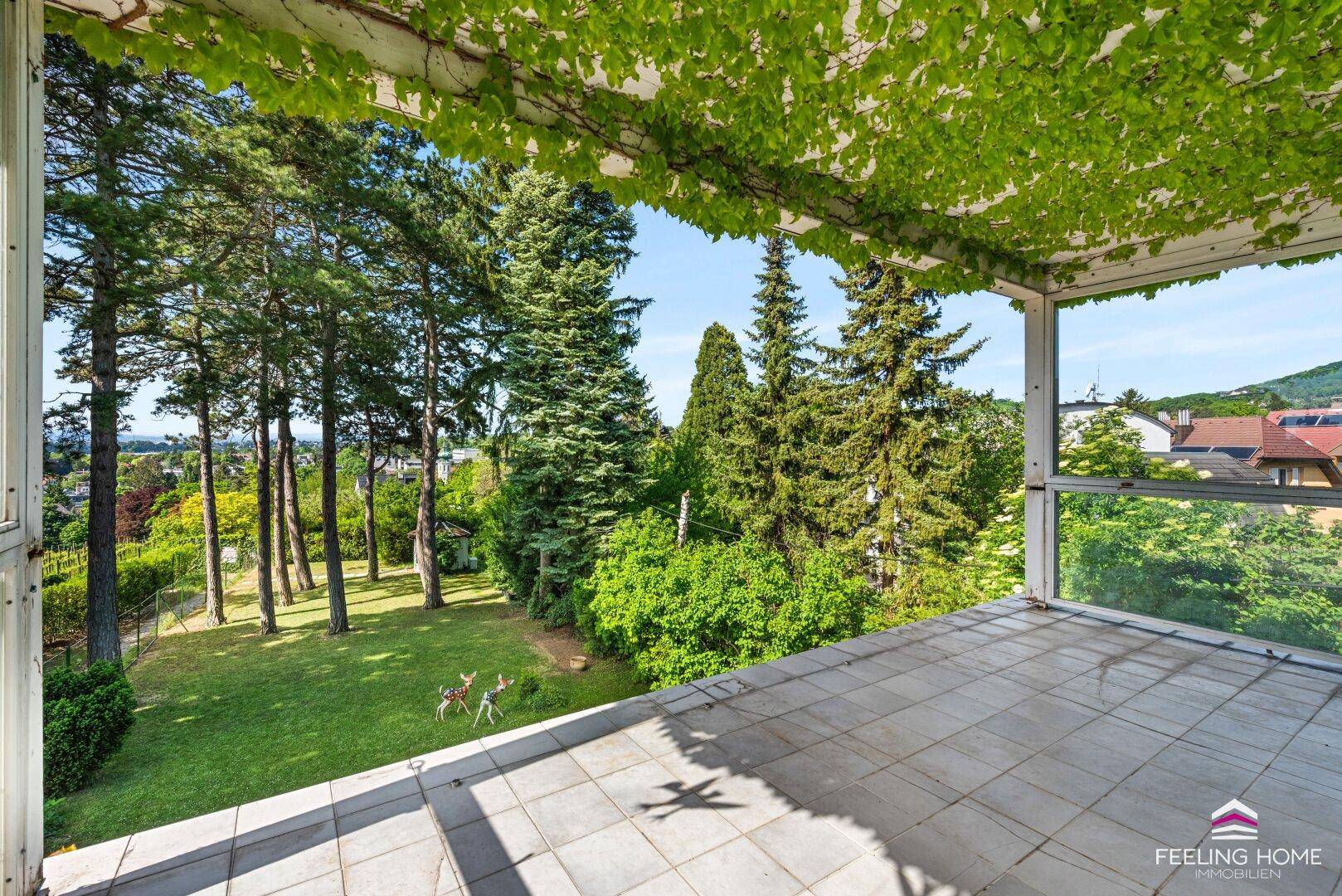 Großer Balkon mit Fliesenboden, üppiger Begrünung und weitem Blick ins Grüne.