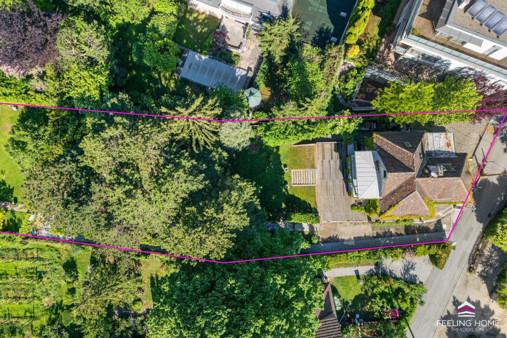 Luftaufnahme eines Anwesens mit großem Garten, Baumbestand und einer Terrasse, umgeben von viel Grün.
