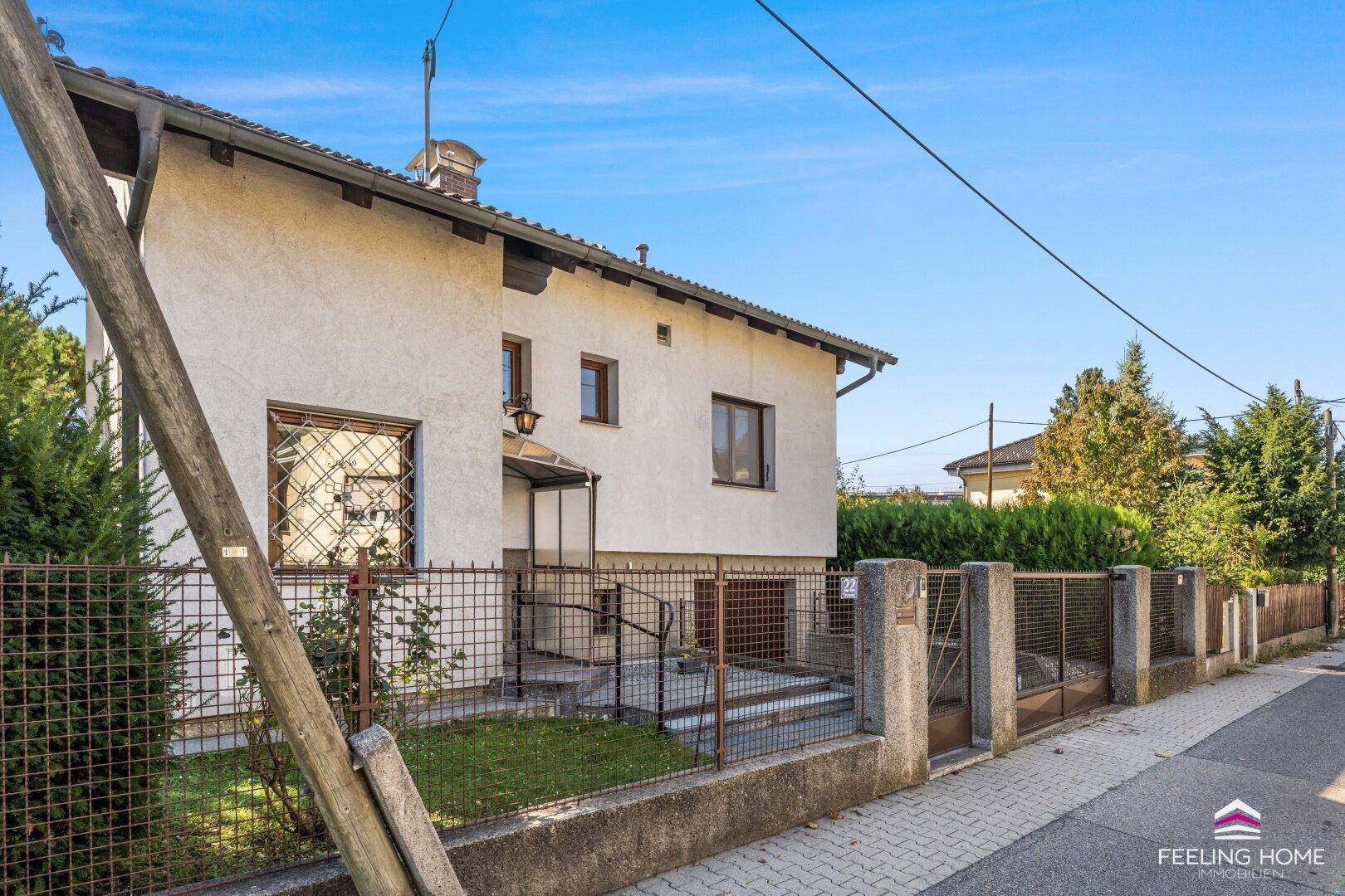 Einfamilienhaus von der Straße aus gesehen mit Zaun und Vorgarten.