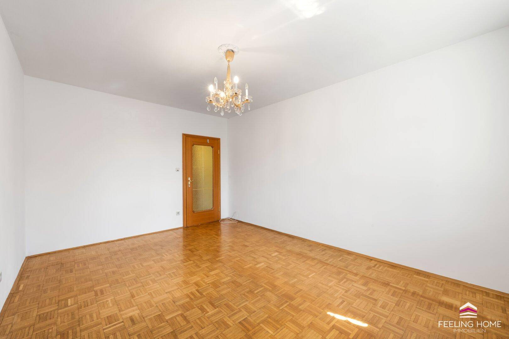Helles Schlafzimmer mit Parkettboden und einer Holztür, bereit zur individuellen Gestaltung.
