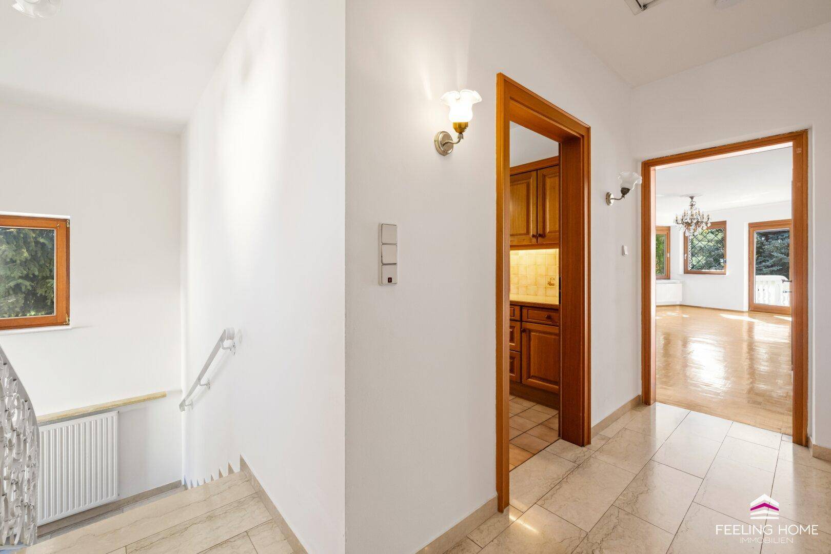 Heller Eingangsbereich mit Fliesenboden, Treppe und Zugang zu Küche und Wohnzimmer.