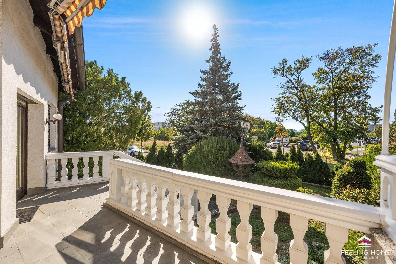 Sonniger Balkon mit klassischem Geländer und weitem Blick ins Grüne und auf die Umgebung.