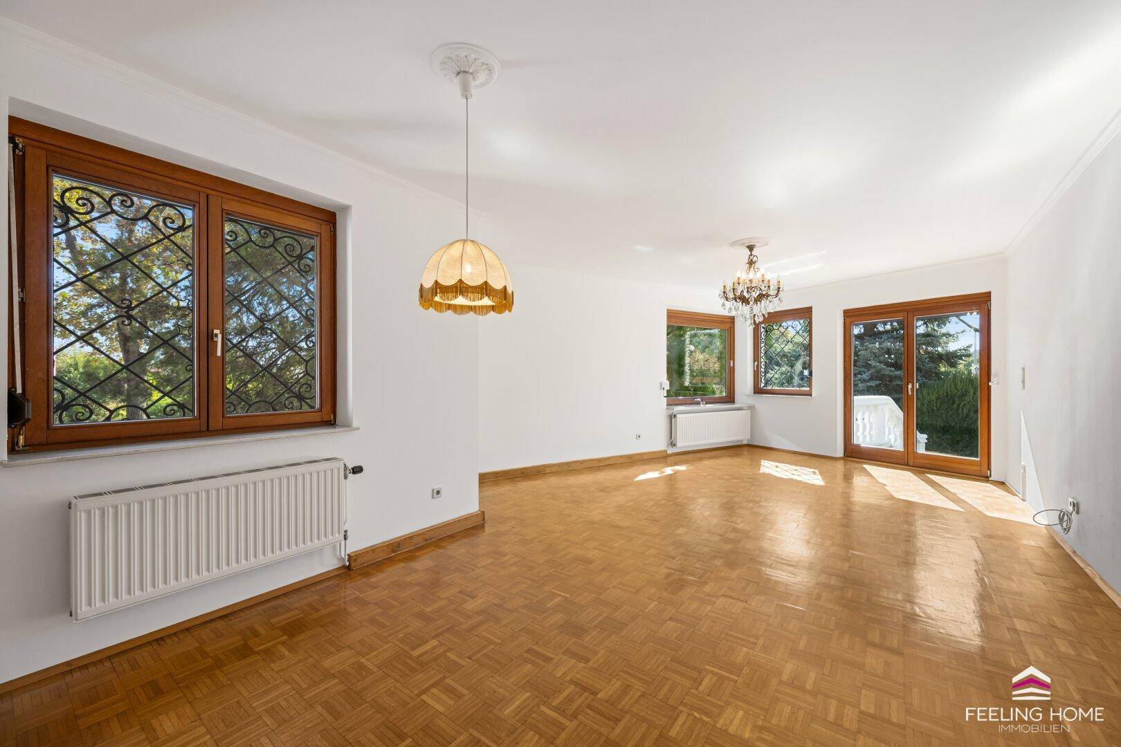 Helles Wohnzimmer mit Parkettboden, großen Fenstern und direktem Zugang zum Balkon.
