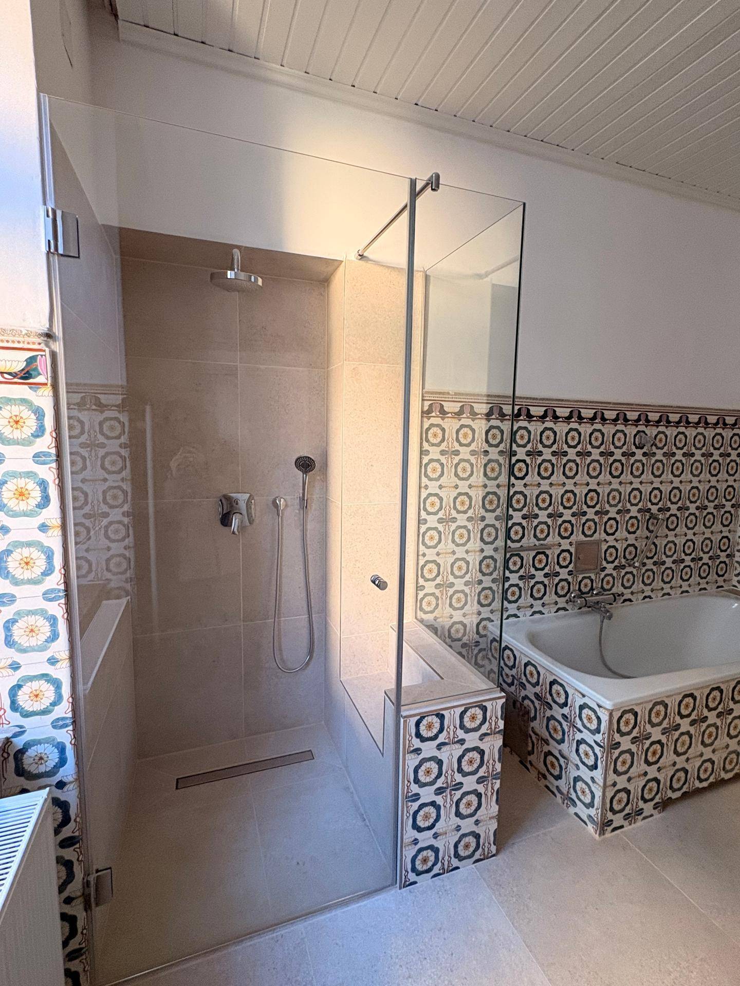 Geräumiges Badezimmer mit begehbarer Dusche, Badewanne und farbenfrohen Wandfliesen, hell und modern.