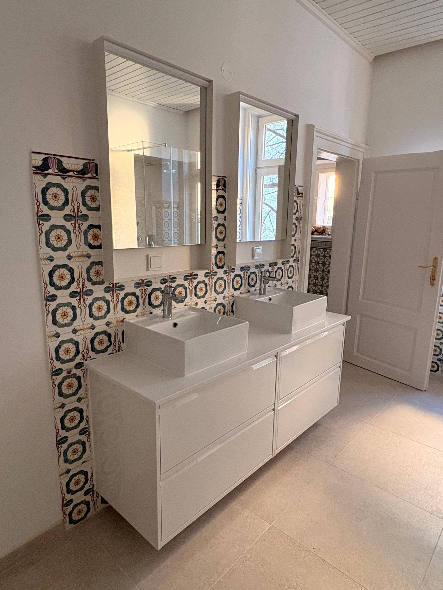 Modernes Badezimmer mit Doppelwaschbecken, großen Spiegeln und dekorativen Fliesen an der Wand.