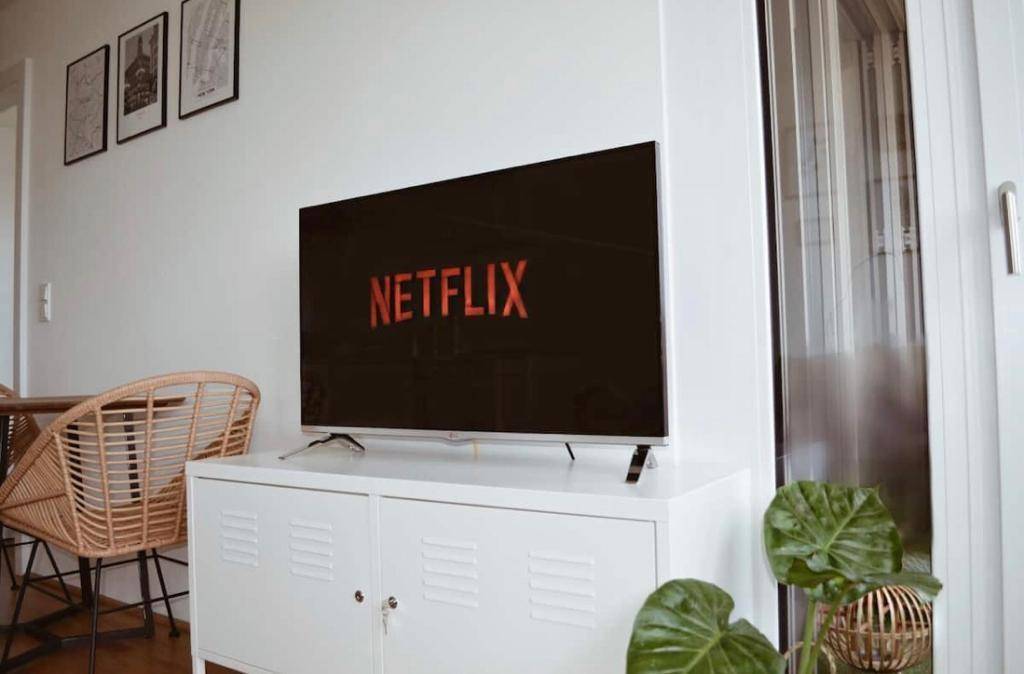 Wohnbereich mit großem Fernseher auf einem weißen Schrank und moderner Einrichtung.