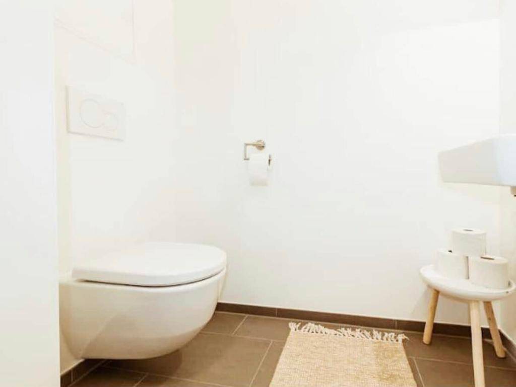 Modernes Gäste-WC mit wandhängender Toilette und Fliesenboden in neutralen Farben.